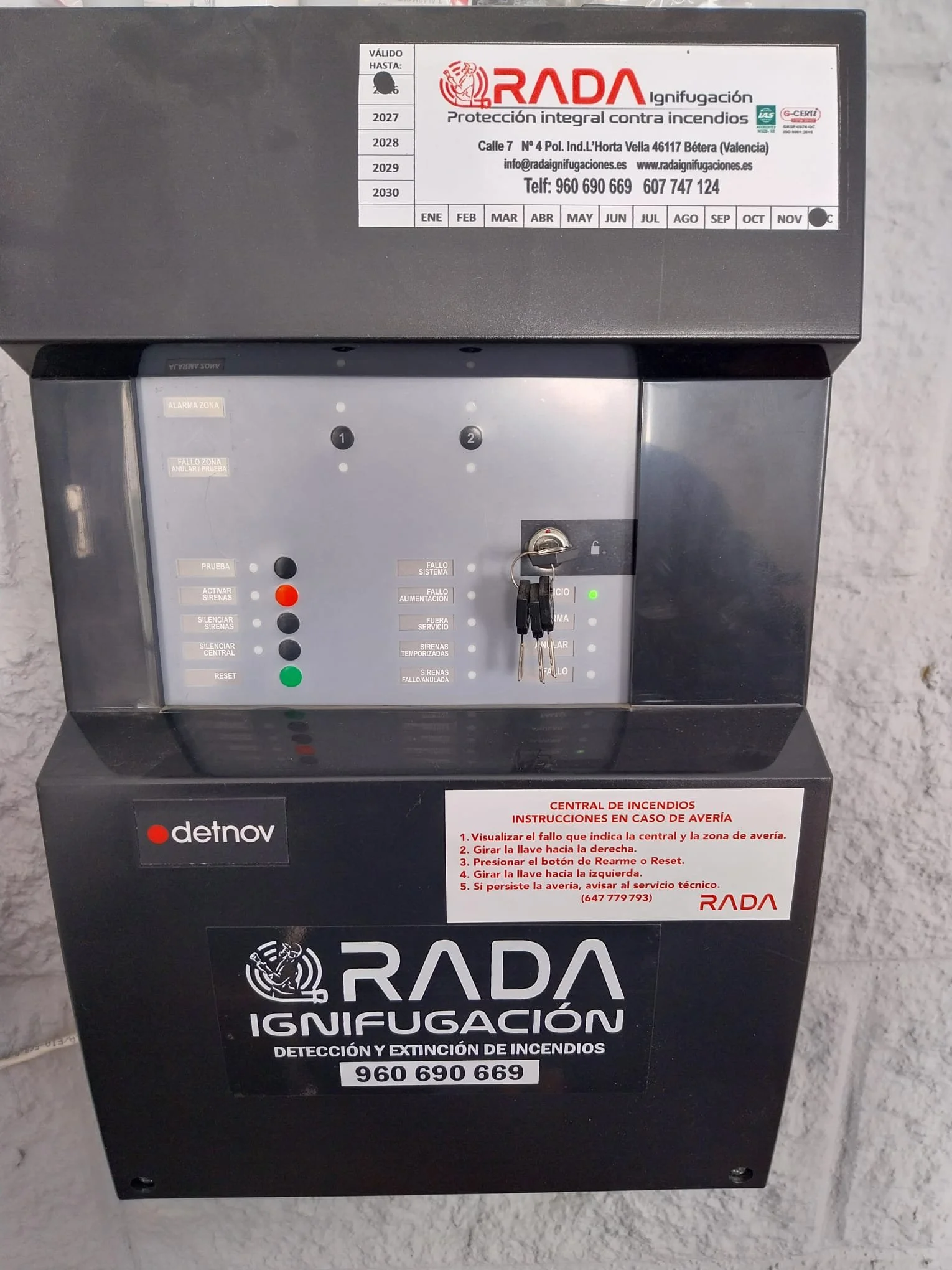Buzón de detección y extinción de incendios, color negro con instrucciones en español y logotipo de RADA, botón de reset, y una llave en la parte central