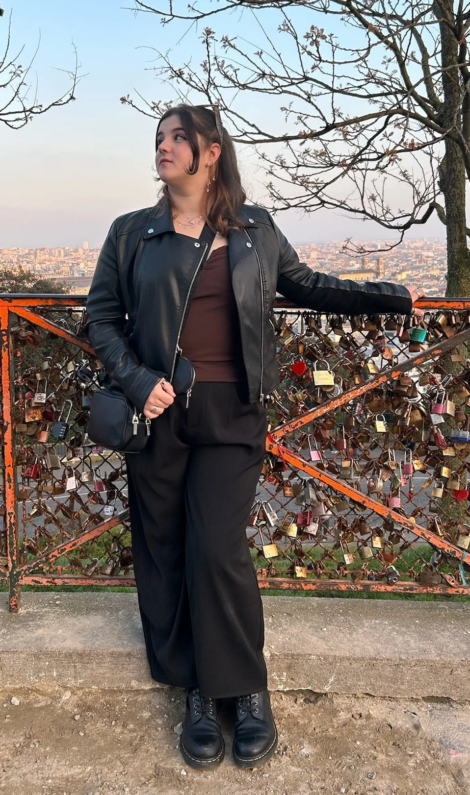 Photo of myself looking to my left, face 3/4 view. I'm standing behind and holding a fence with my left hand, littered with locks from previous visitors immortalising their love