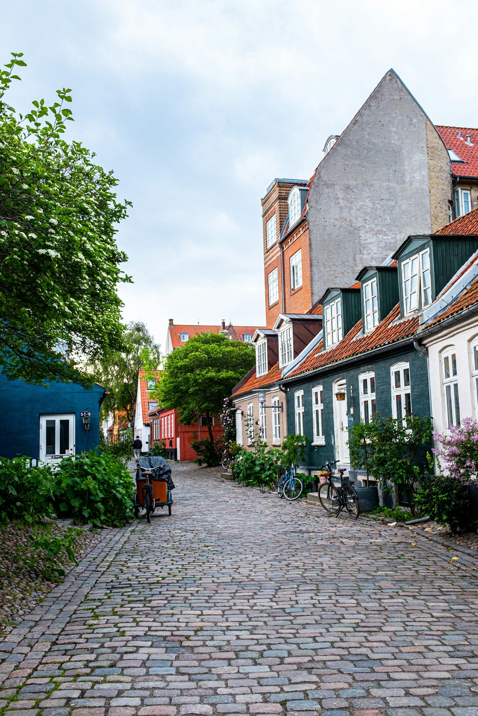Colourful historic houses and bicycles lining a peaceful cobbled street in Aarhus, Denmark.