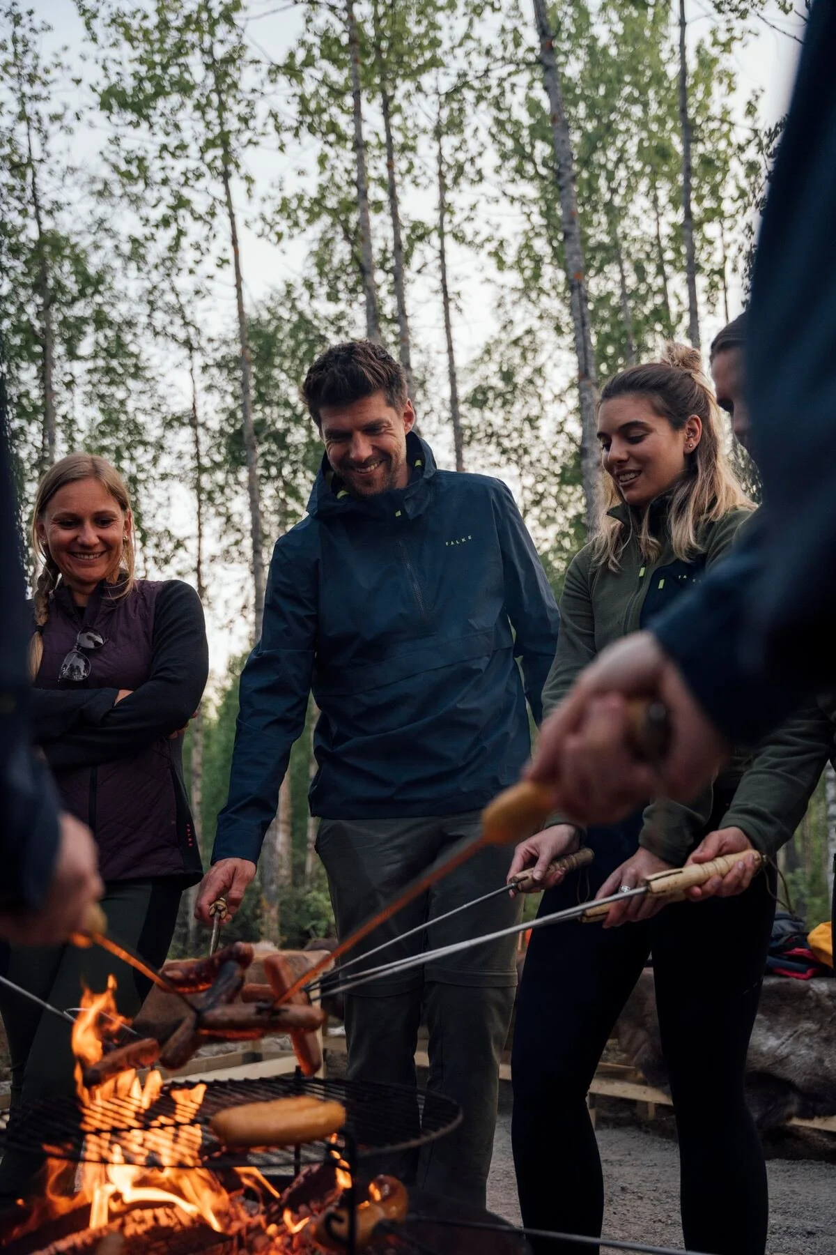Travellers cook sausages over an open campfire surrounded by forest in Finland.