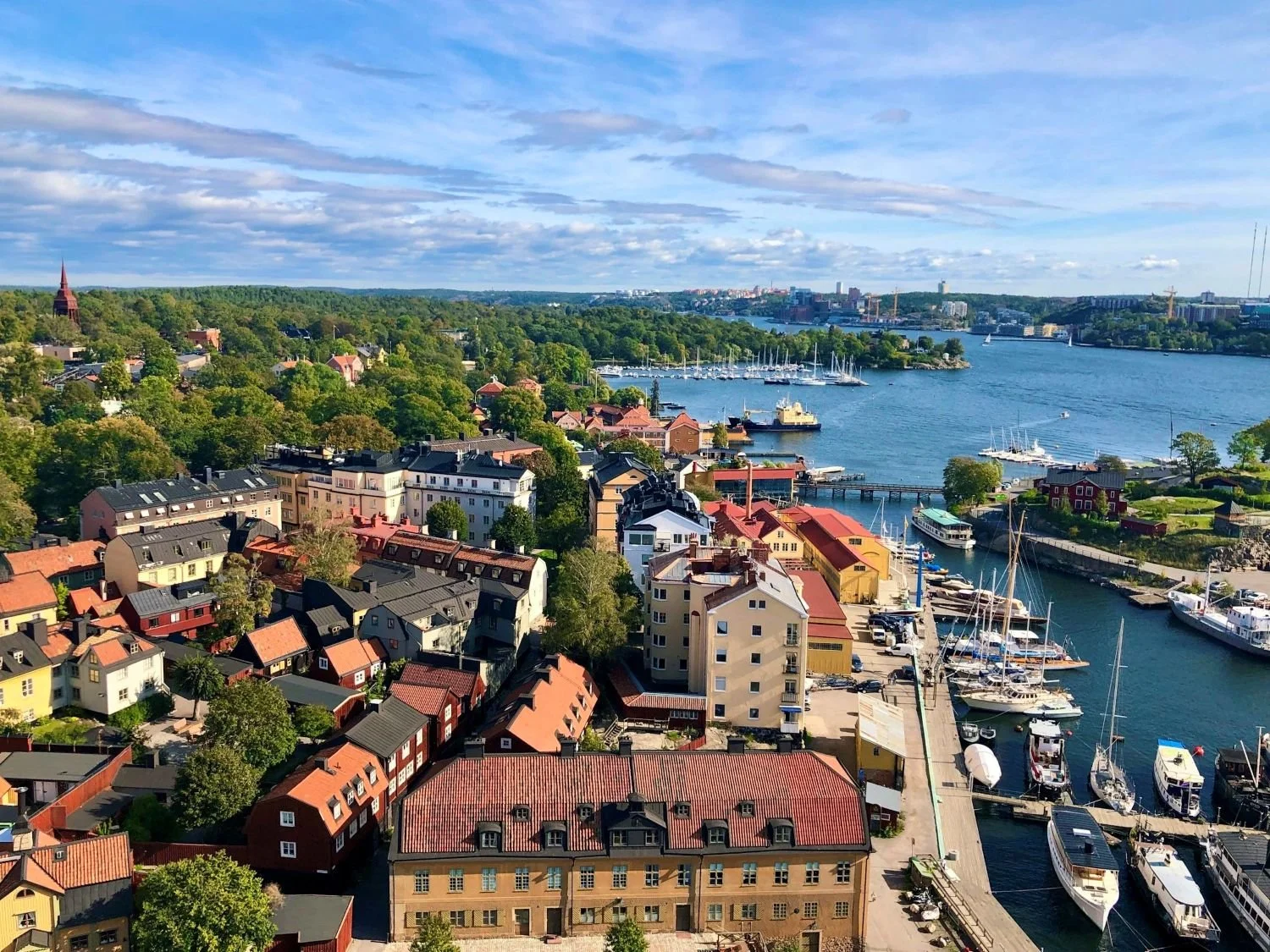 Panoramic view across Stockholm’s colourful waterfront, marinas and green islands on a summer day.