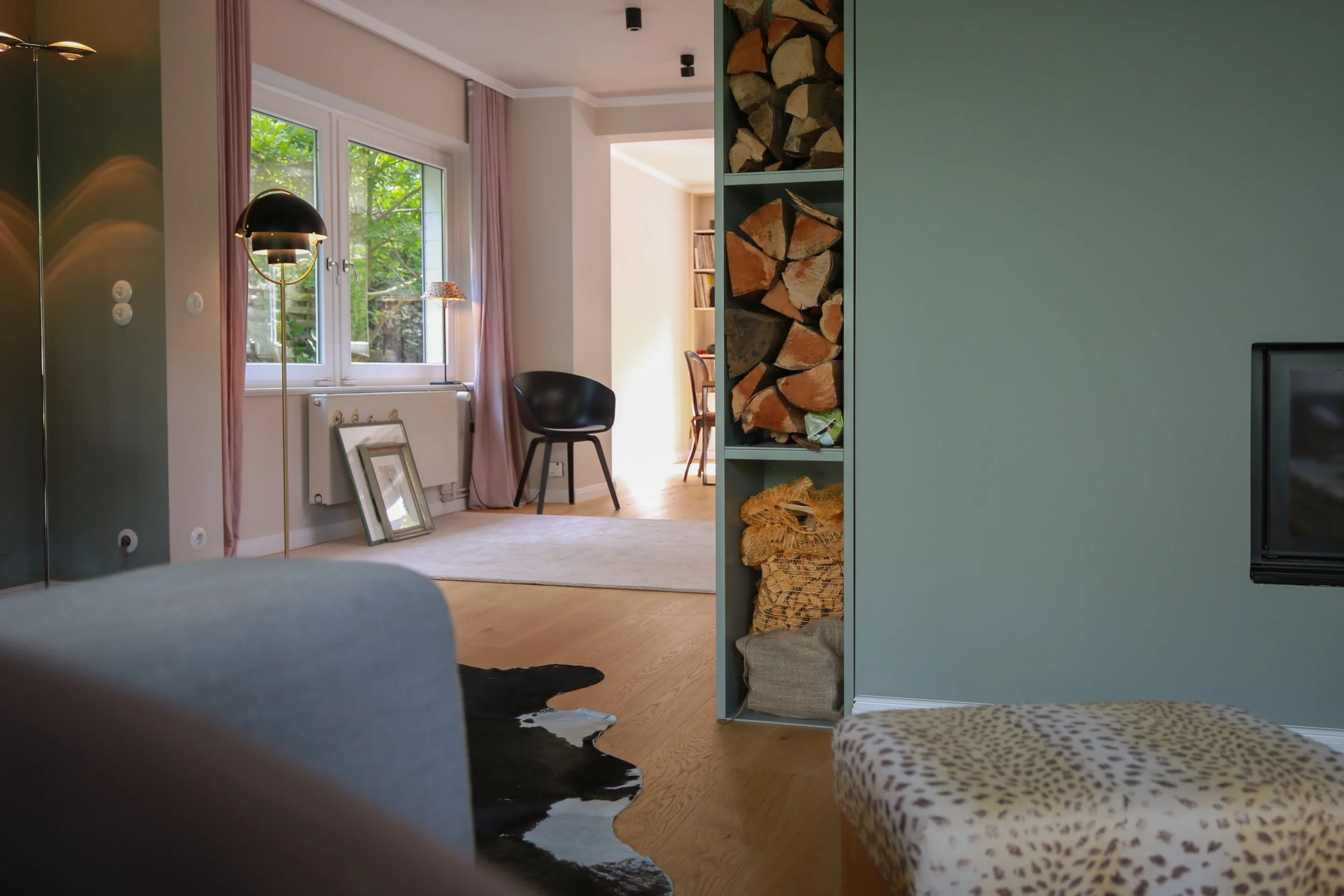 Durchdachtes Interior Design mit maßgefertigtem Raumteiler, integriertem Kamin und Holzlager sowie Blick in den angrenzenden Wohnbereich.