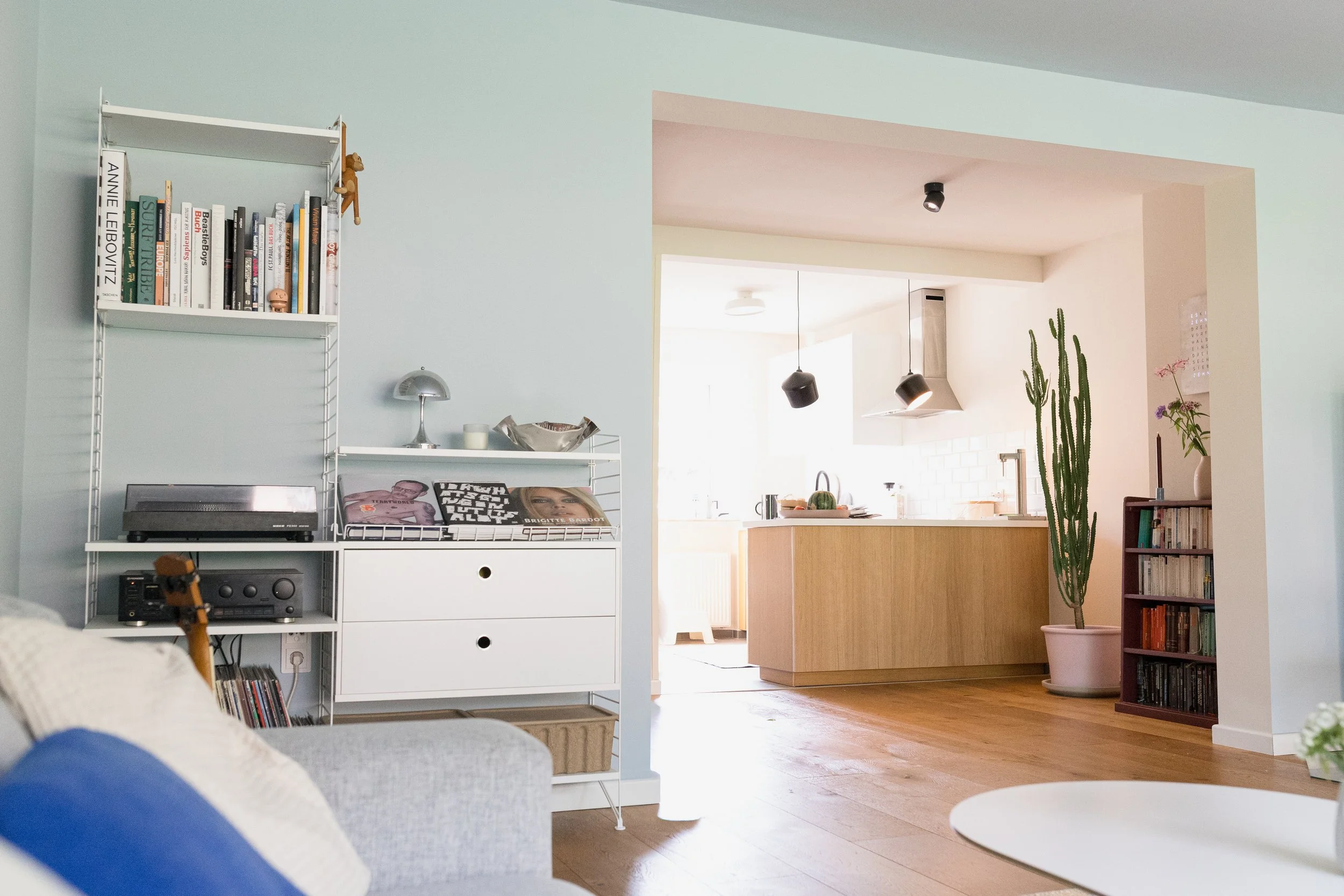Blick vom Wohnbereich in die offene Küche mit abgestimmten Blau-, Sand- und Holztönen – Interior Design in Hamburg-Rissen.