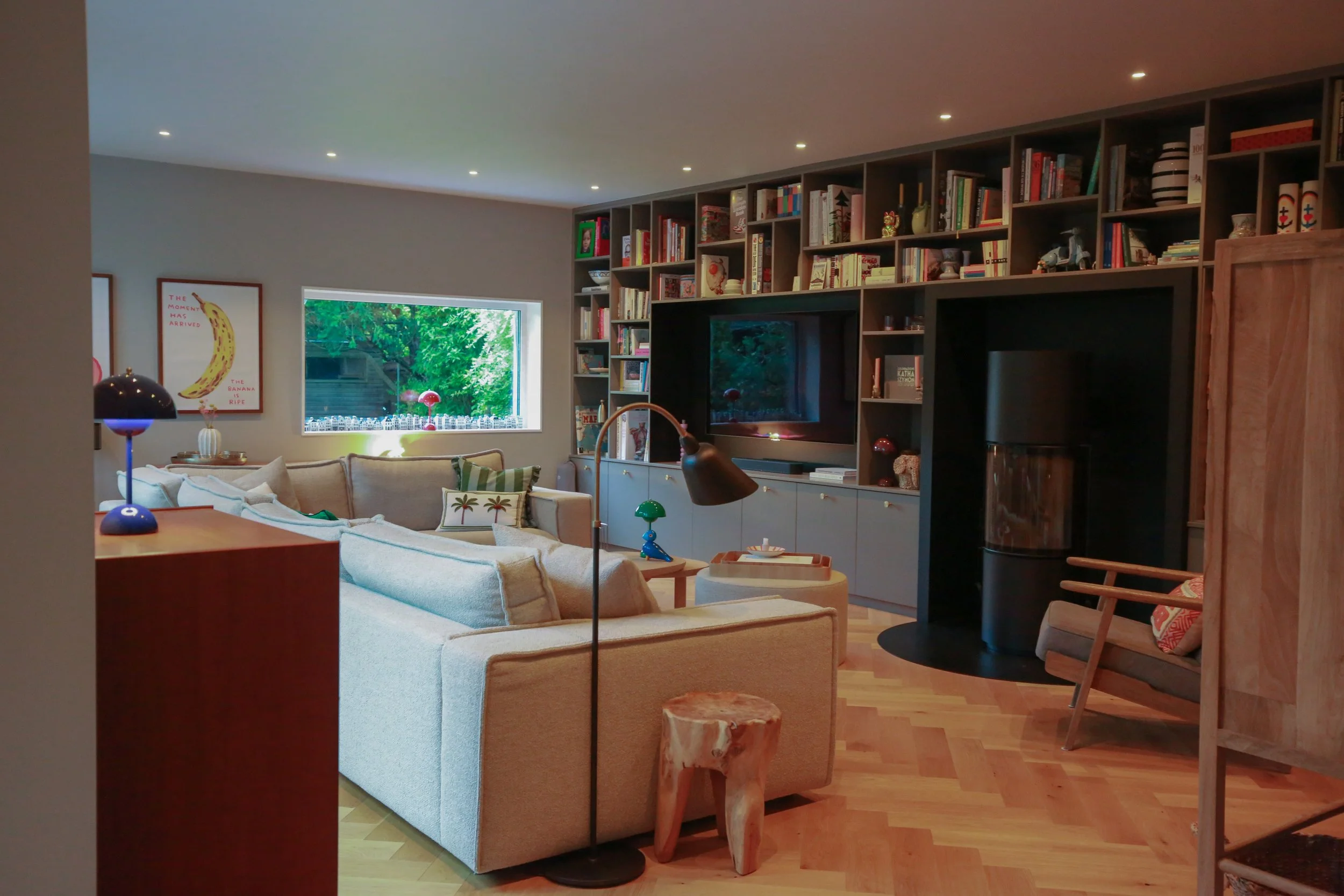 Wohnzimmer mit maßgefertigter Regalwand, integriertem Kamin und Fischgrätparkett in einem Architektenhaus in Hamburg-Rissen.