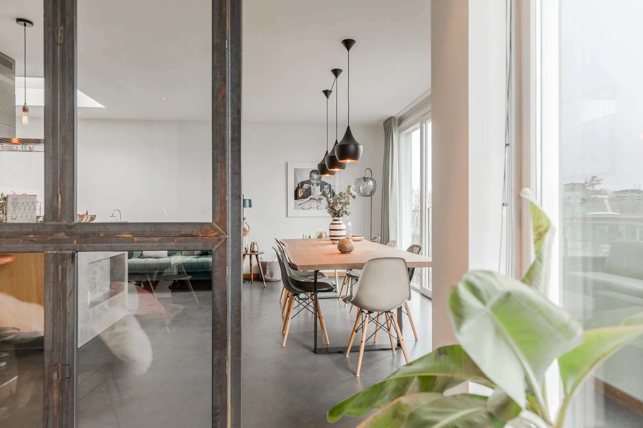 Offener Wohn- und Essbereich eines Penthouses in Amsterdam mit Betonboden, warmem Holz, Vintage-Elementen und industriellen Details.