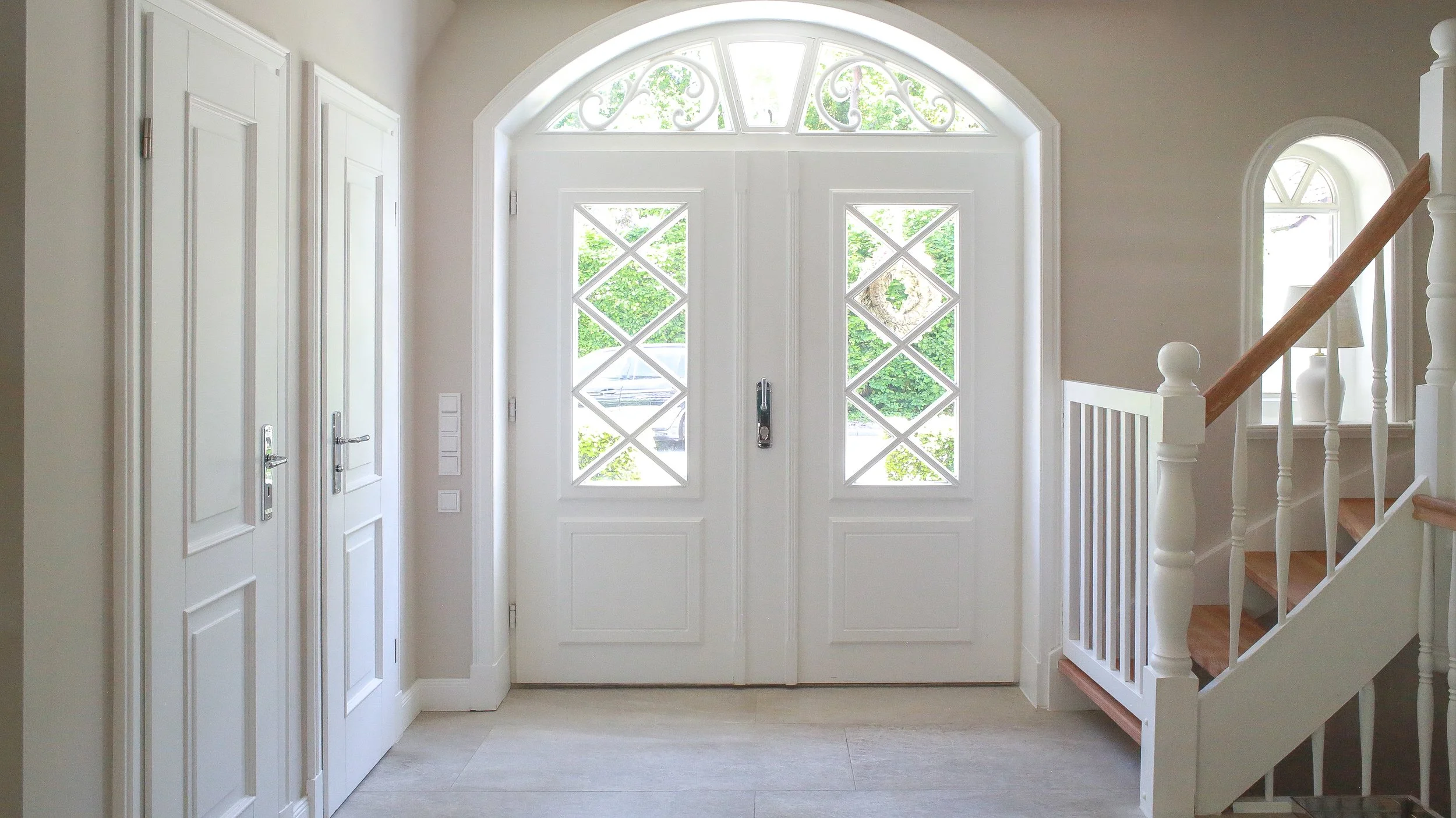 Helles Entrée eines Landhauses in Hamburg-Rissen mit klassischer Treppe und großzügiger Eingangstür – ruhiges, zeitloses Farb- und Raumkonzept.