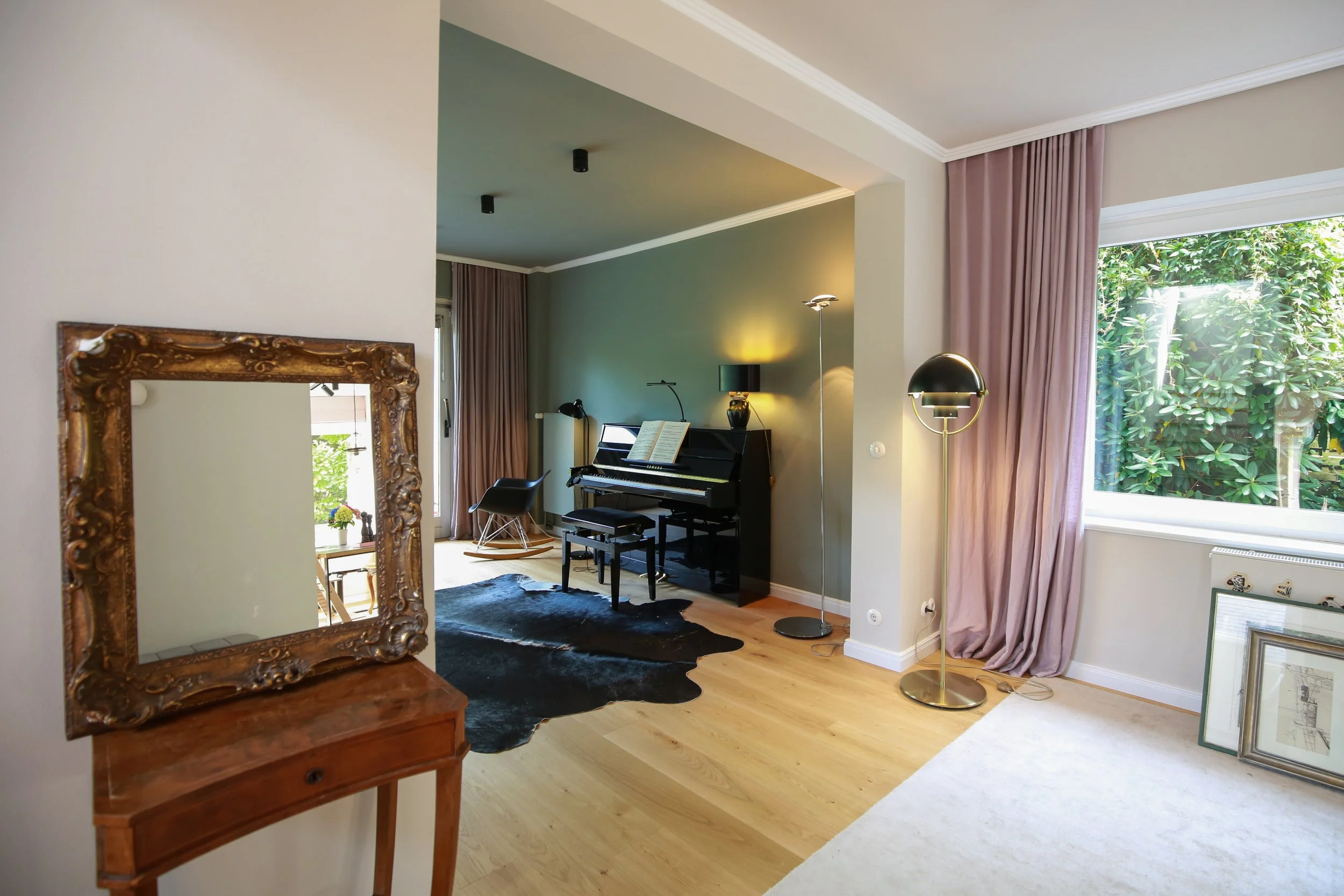 Wohnraum mit Klavier, Vintage-Möbeln und sanftem Farbkonzept in Grün und Rosé – individuelle Interior-Design-Planung in Hamburg.