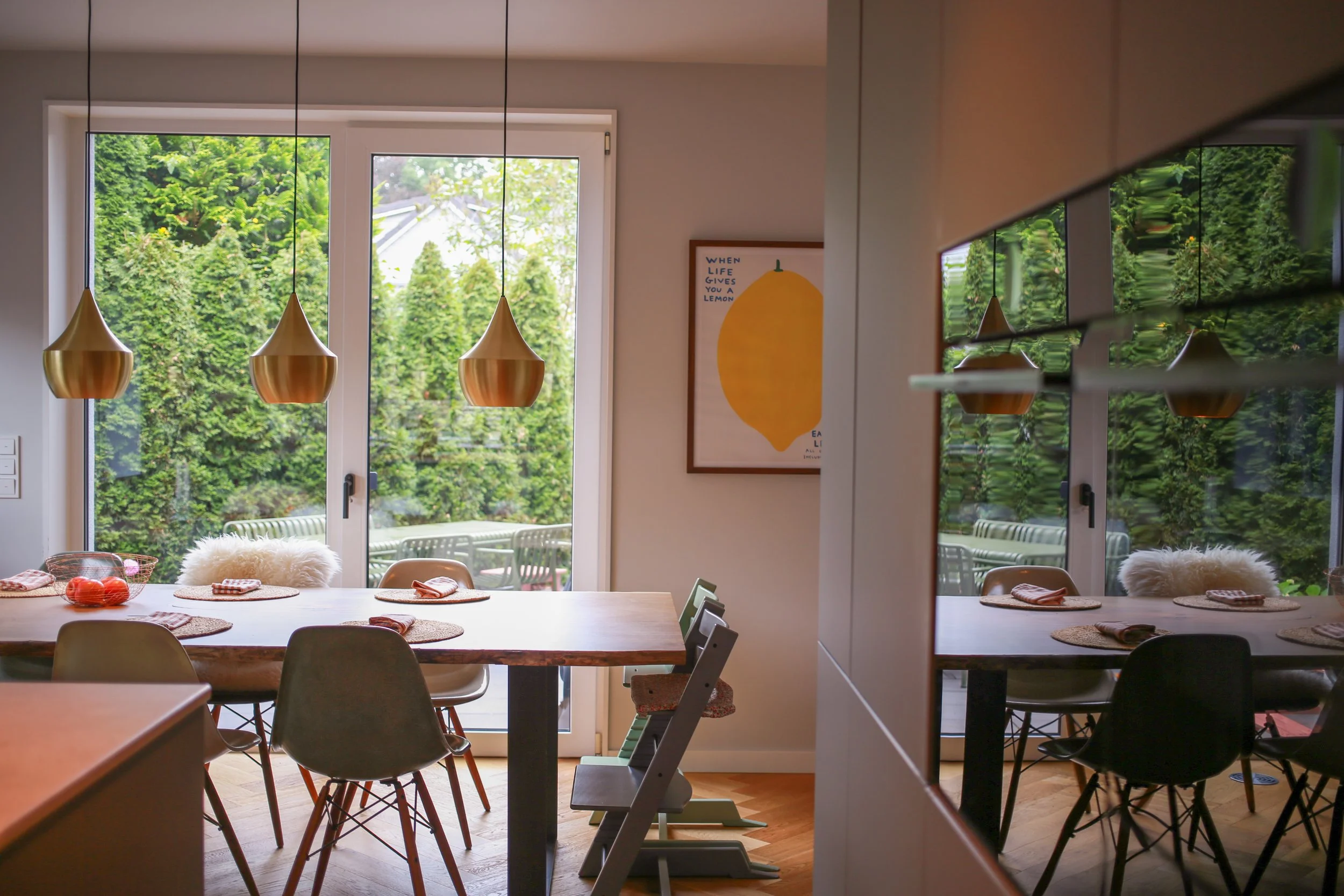Essbereich mit Holztisch, Designstühlen und Messingleuchten im Architektenhaus in Hamburg-Rissen.