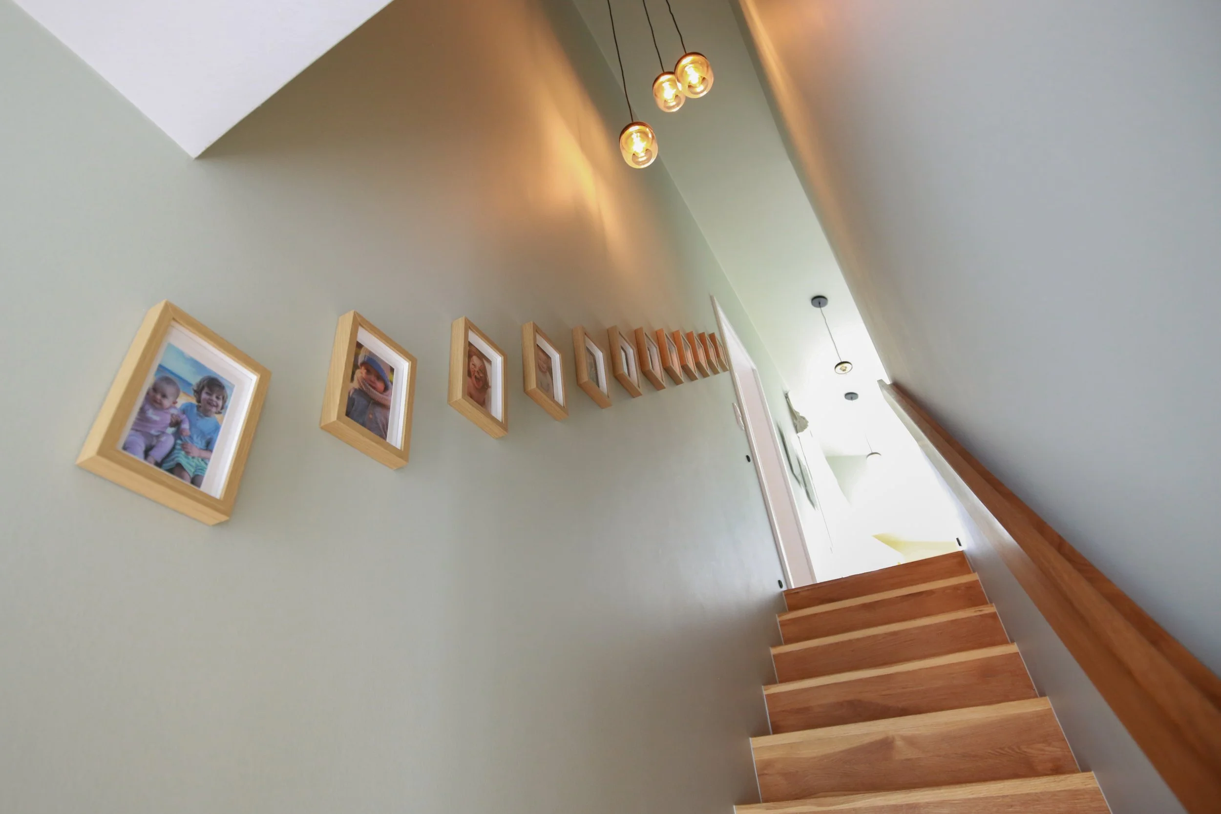Treppenhaus mit Holztreppe, Bildergalerie und individuellem Licht- und Farbkonzept in einem Architektenhaus in Hamburg.