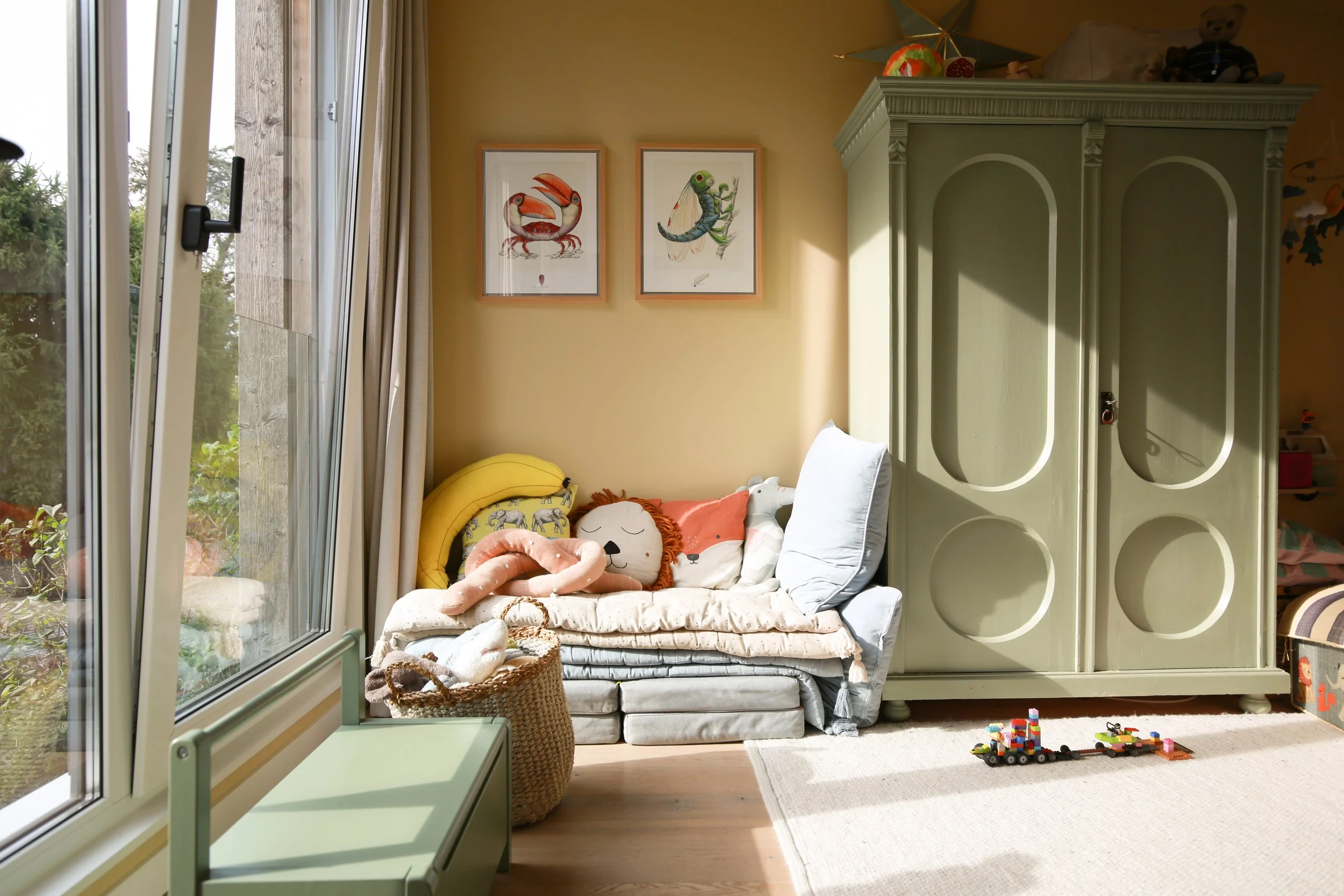 Kinderzimmer mit Farrow & Ball Hay – ein warmer, gedeckter Gelbton als Hintergrund für Holz, Farbe und persönliche Lieblingsstücke.