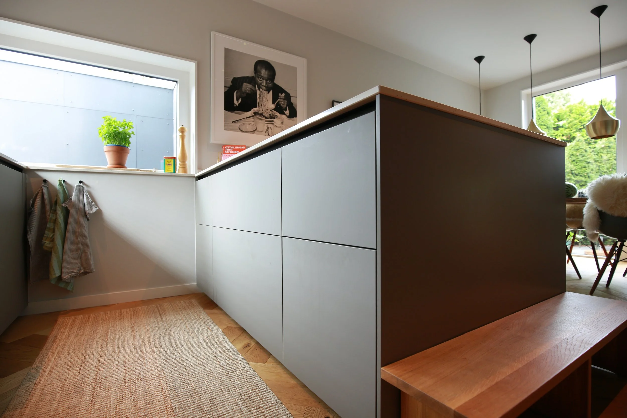 Moderne Küche mit Kücheninsel, grauen Fronten und warmen Holzdetails als Teil eines ganzheitlichen Interior-Konzepts.