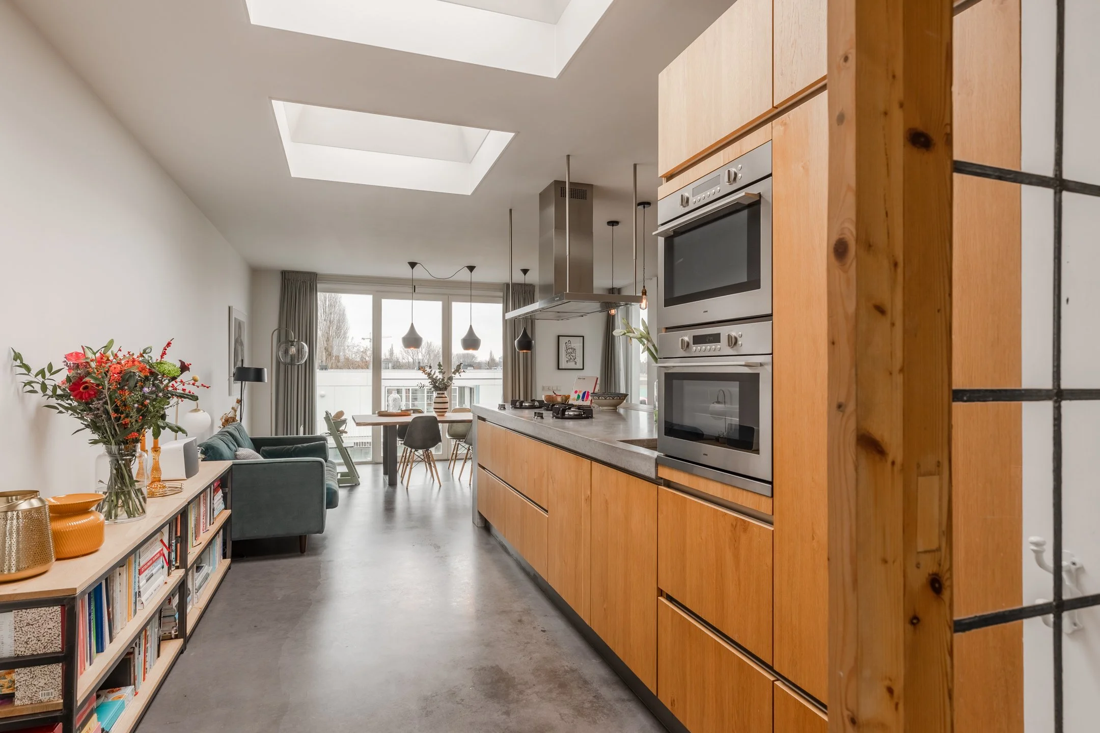Maßgefertigte Küche mit Holzfronten, Betonarbeitsfläche und Oberlichtern – Materialkonzept für ein modernes Penthouse in Amsterdam.