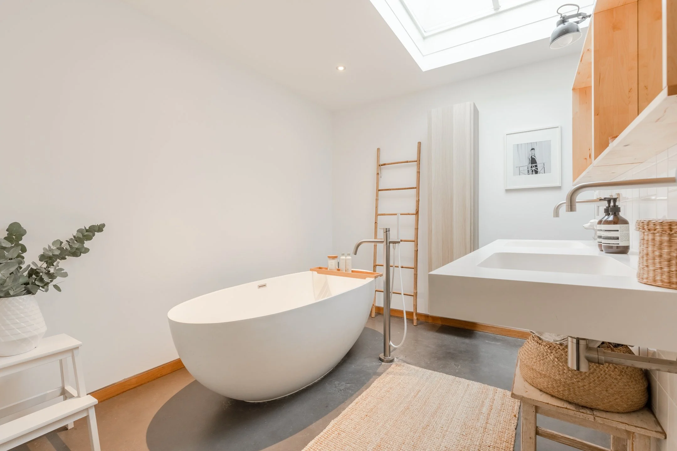 Helles Badezimmer mit freistehender Badewanne, Betonboden, natürlichen Materialien und reduziertem Interior-Konzept.