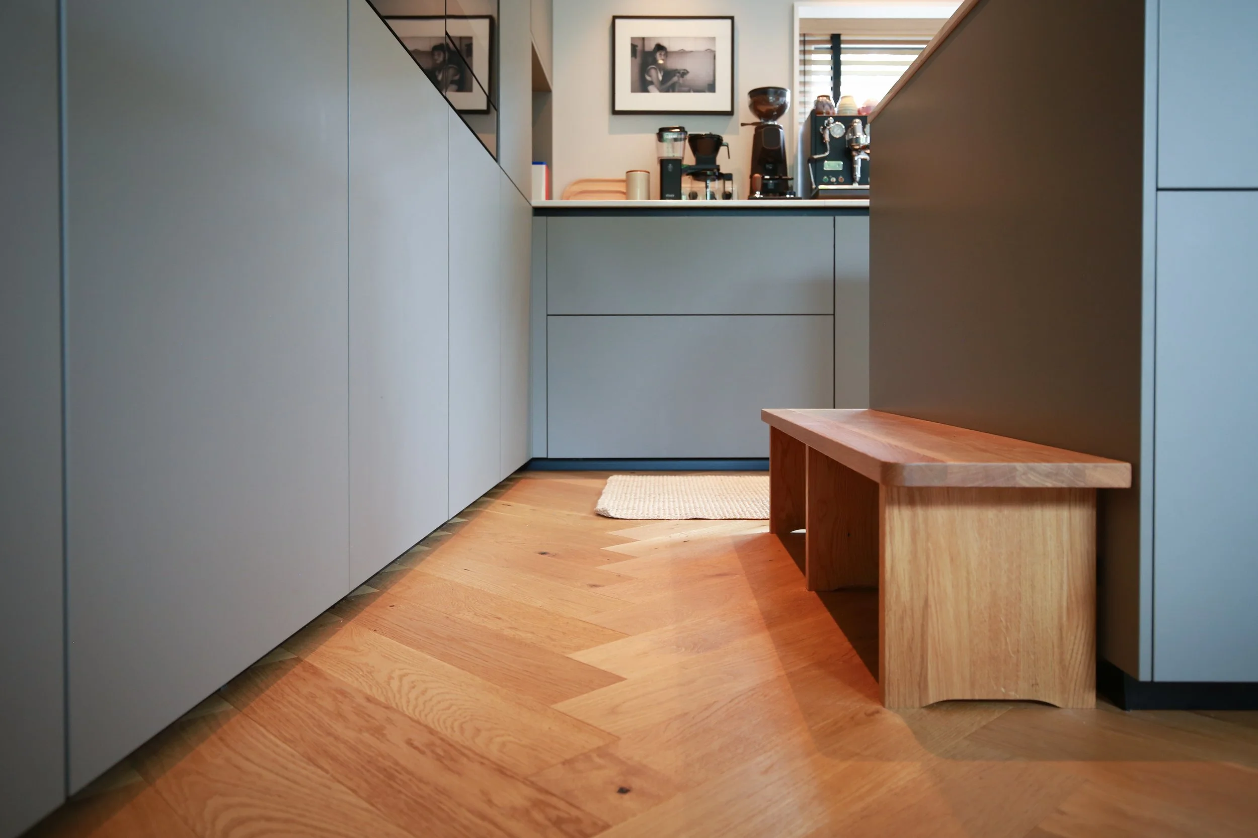 Individuell geplante Küche mit grauen Fronten, Holzdetails, Sitzbank und Fischgrätparkett in einem Architektenhaus in Hamburg.