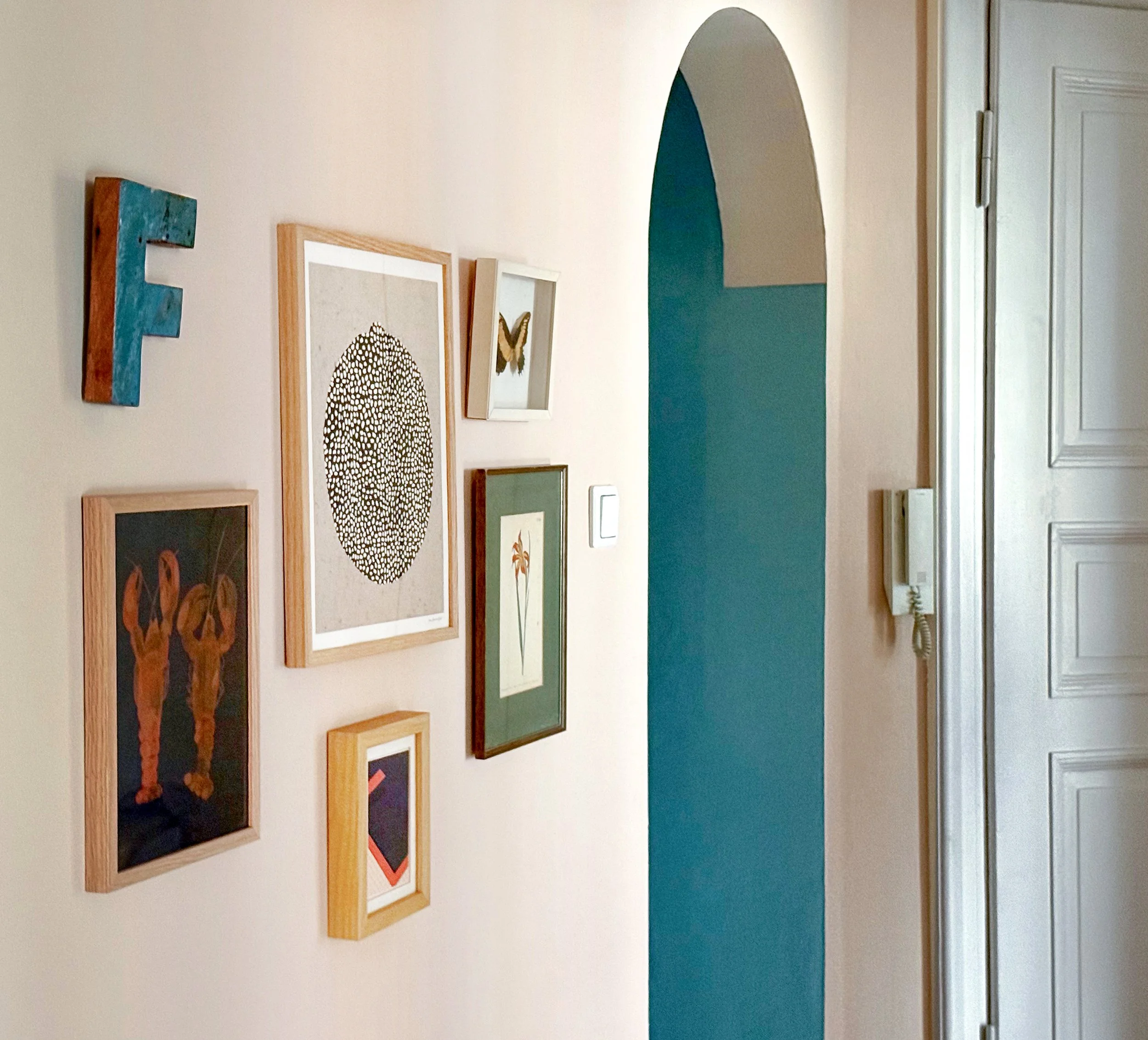 Altbauflur in München mit Bilderwand und kontrastreichem Farbkonzept in Rosé und tiefem Blau-Grün – historische Architektur modern interpretiert.
