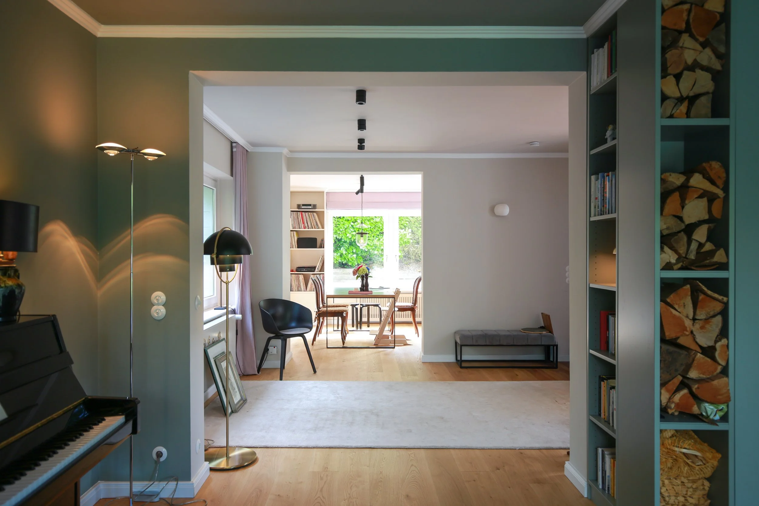 Ganzheitliches Raumkonzept mit fließenden Übergängen zwischen Wohnzimmer, Essbereich und Küche sowie individuell abgestimmten Farben und Materialien.