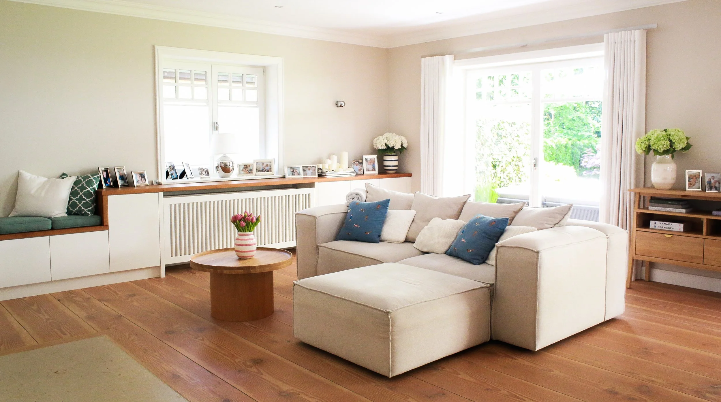 Helles Wohnzimmer mit großzügigem Sofa, warmen Holzböden und sanften Blau- und Naturtönen – Interior Design für ein Landhaus in Hamburg-Rissen.