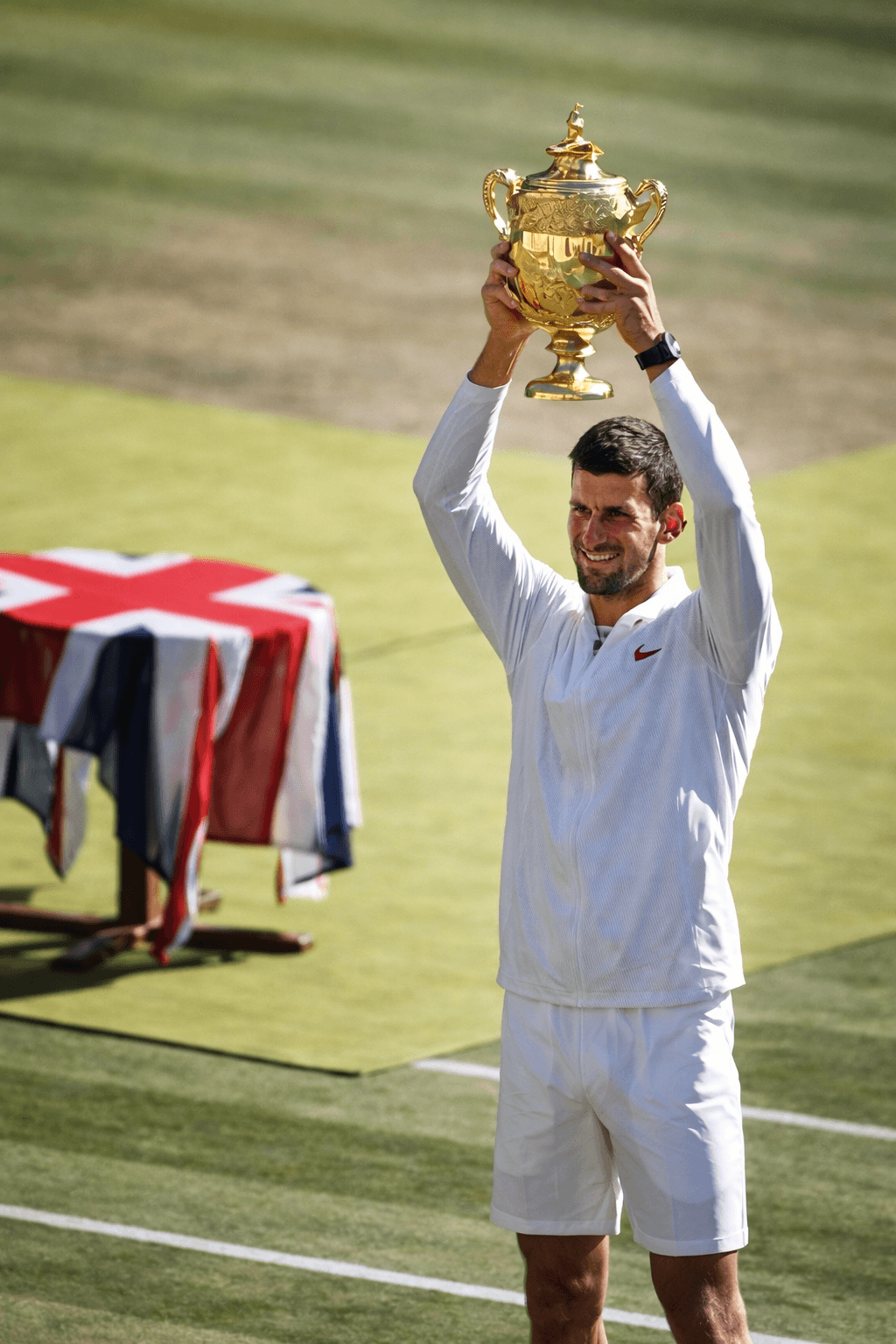 Novak Djokovic holding the golden trophy above his head Wimbledon Central Court