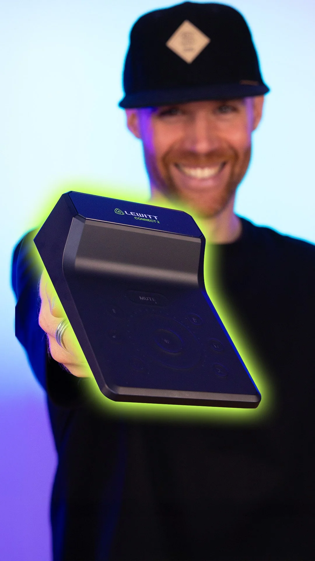 Erik van der Ven in a black cap holding a LEWITT Connect 2 Interface, against a colorful background.