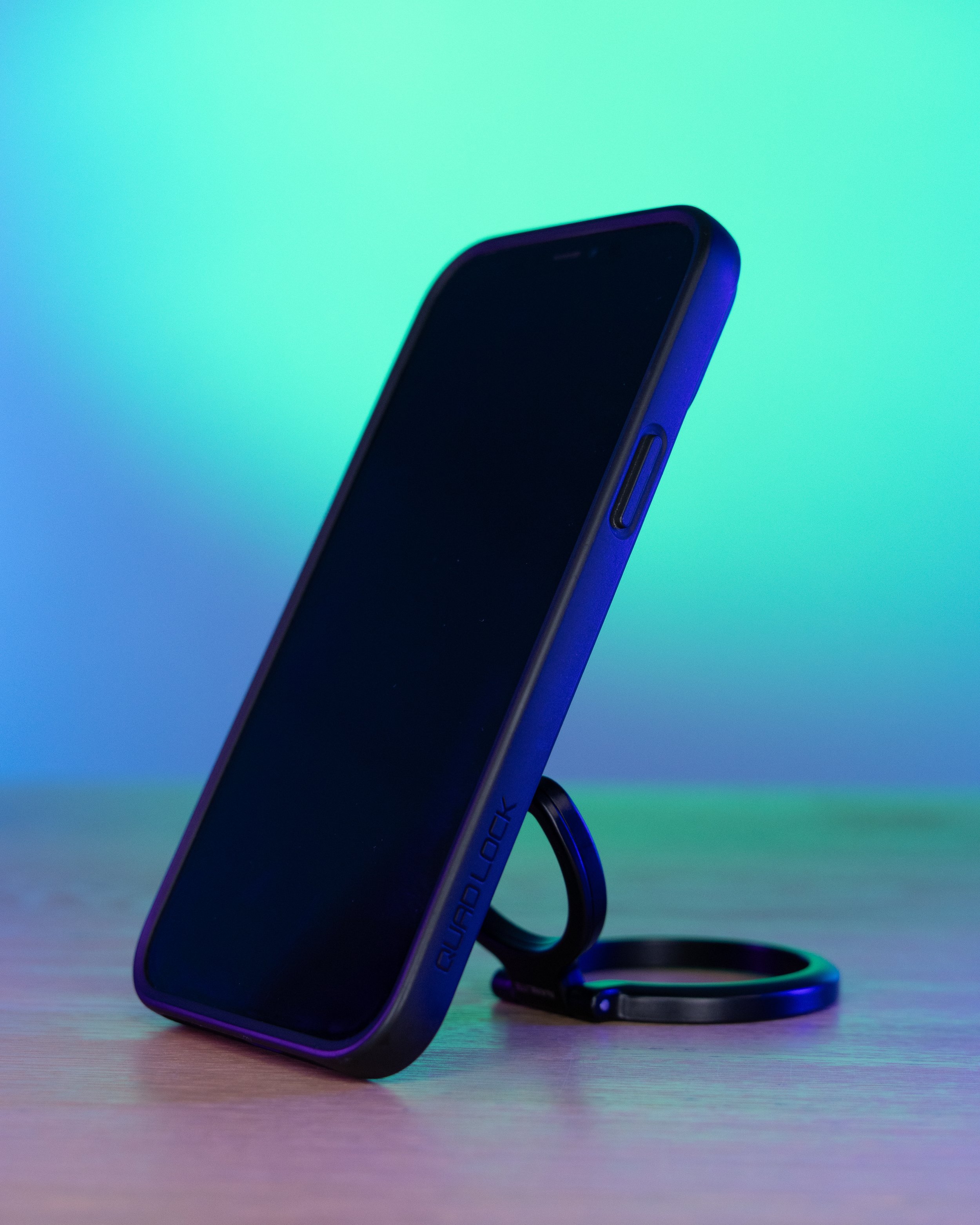 Smartphone with a black screen on a stand with colorful ambient lighting.