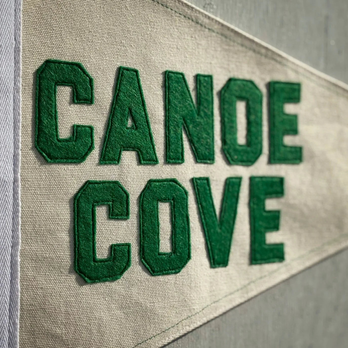 Close-up of a fabric patch with green embroidered letters spelling 'CANOE COVE.'