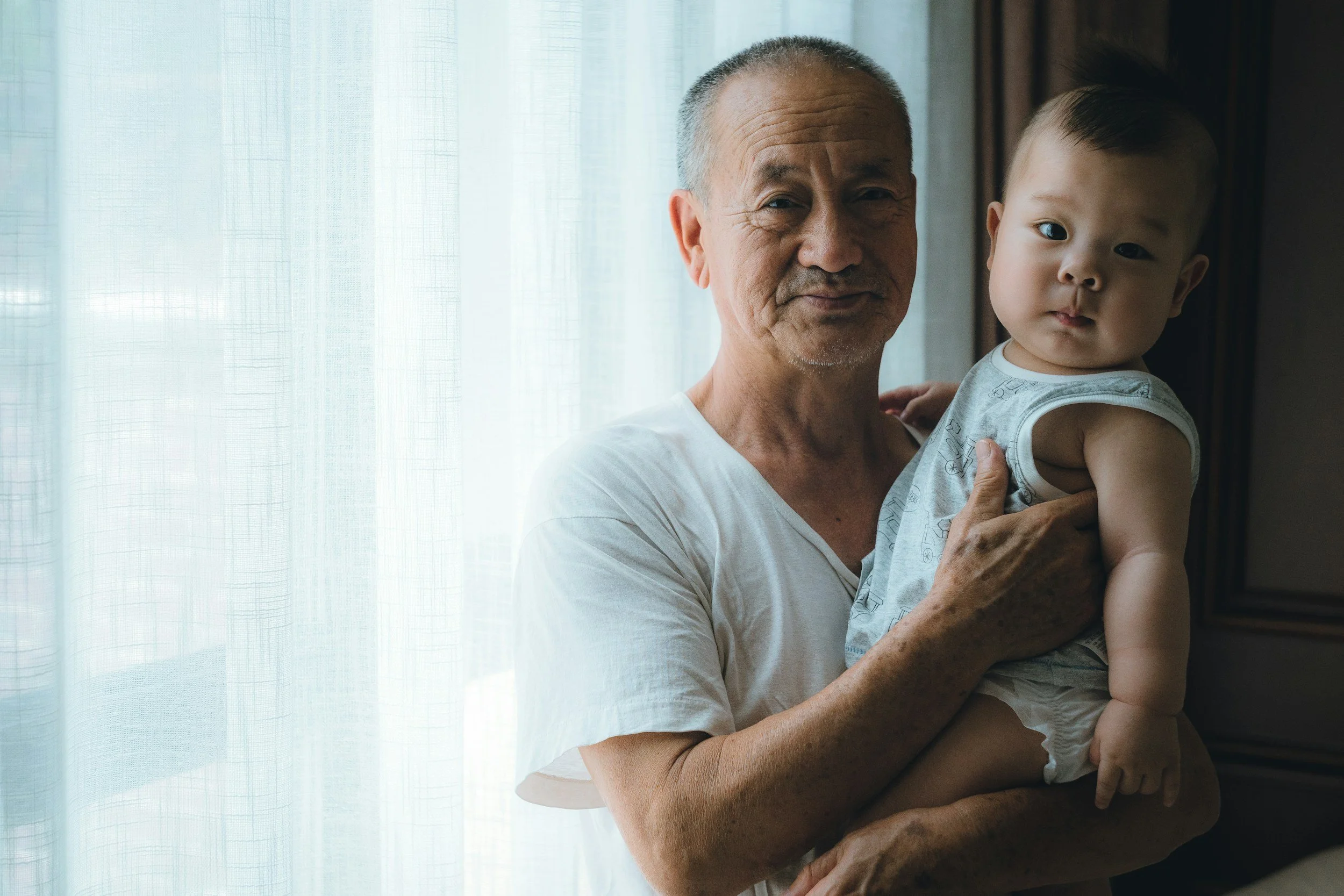 A grandfather holds his grandbaby. A postpartum doula in St. Louis can help give grandparents tips.