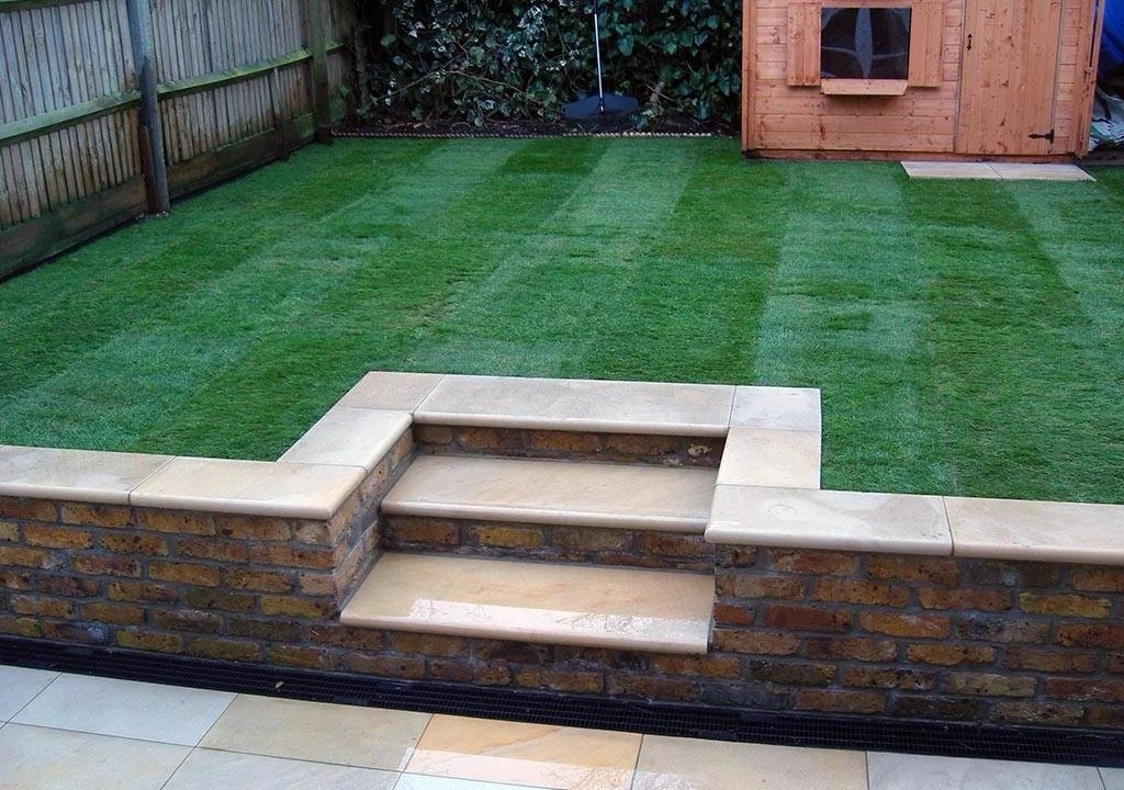 Backyard with freshly laid grass, brick steps, and a wooden shed.