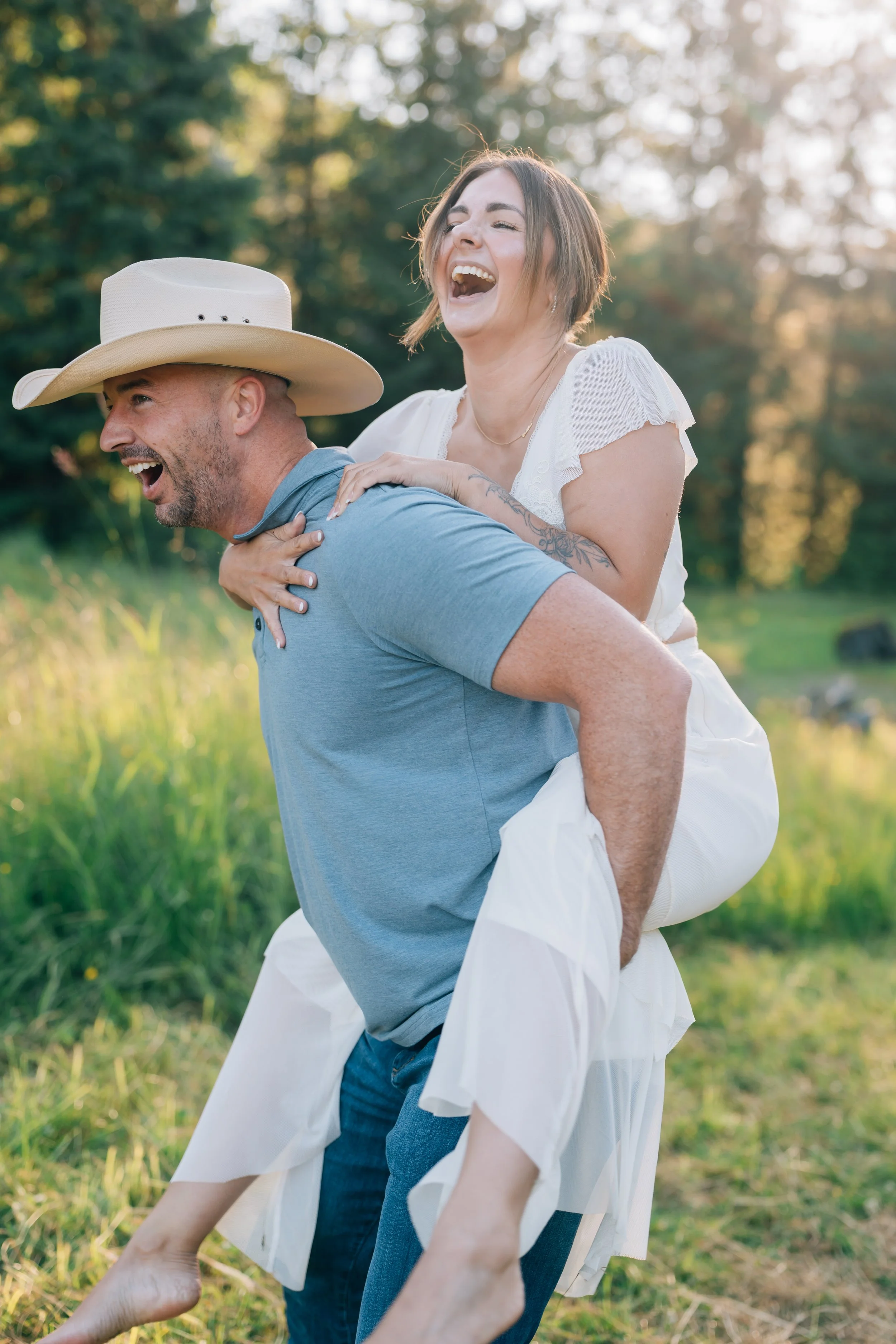 guy carries girl on his back while laughing at their engagement photo session in juneau