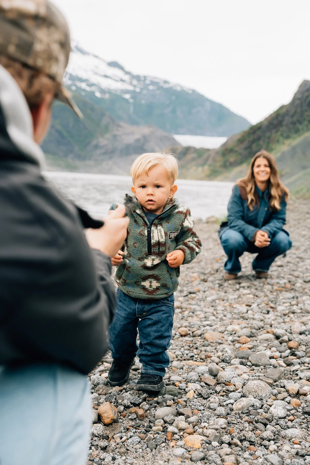 A little boy hands dad a rock on the shores of mendenhall lake during their juneau family photos