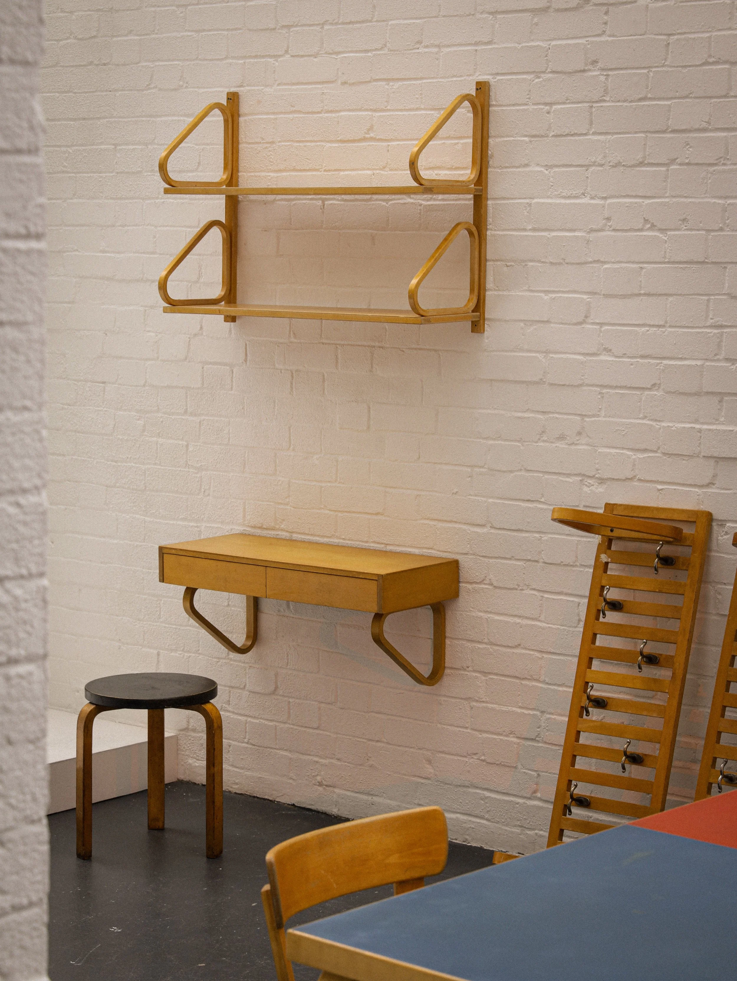 Interior of a room with a white brick wall, featuring various iconic Finnish design pieves such as Alvar Aalto, Arne Jacobsen, Jean Prouve, Vico Magistretti