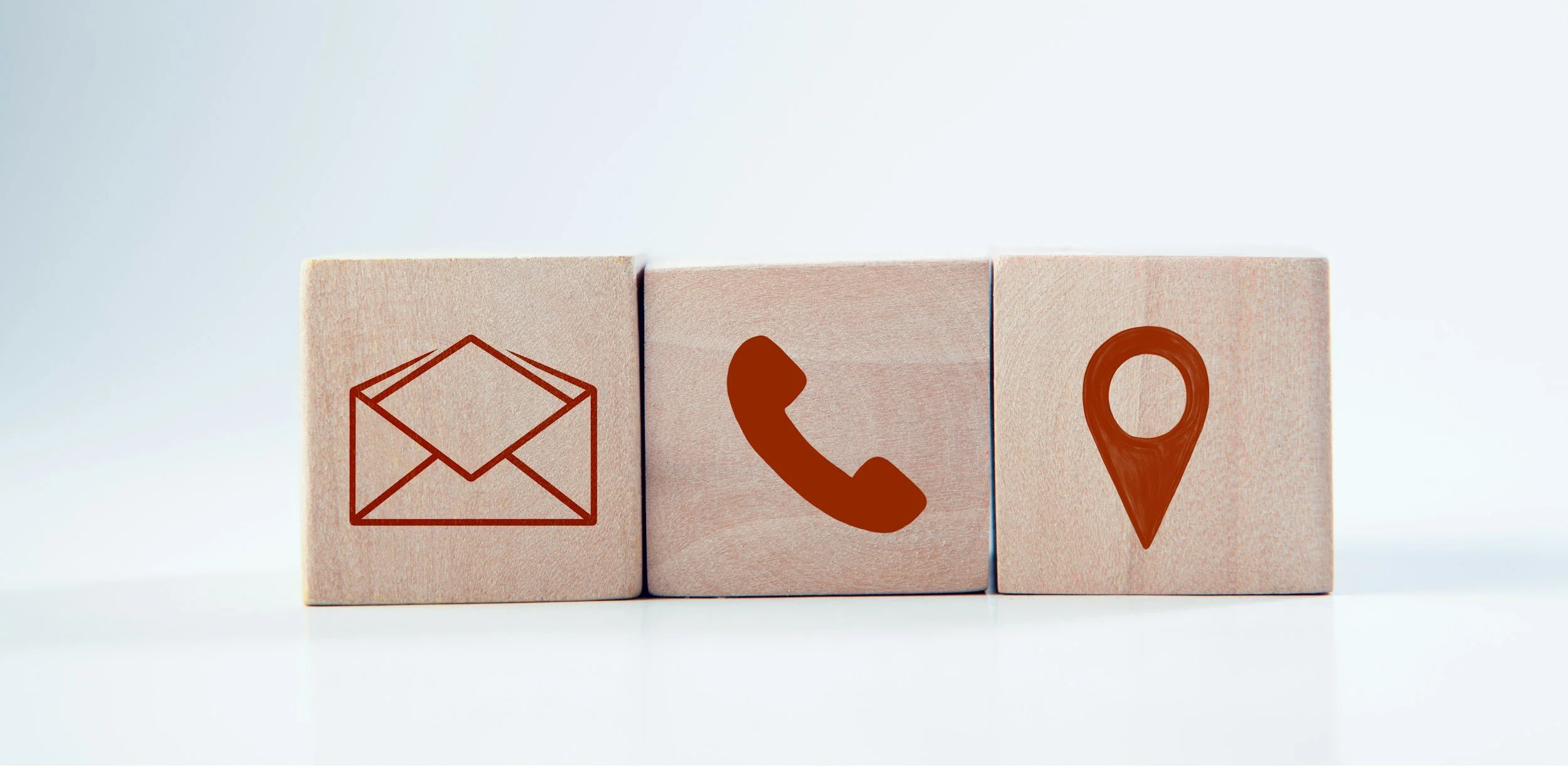 Three wooden blocks with icons: an envelope, a phone, and a location pin.