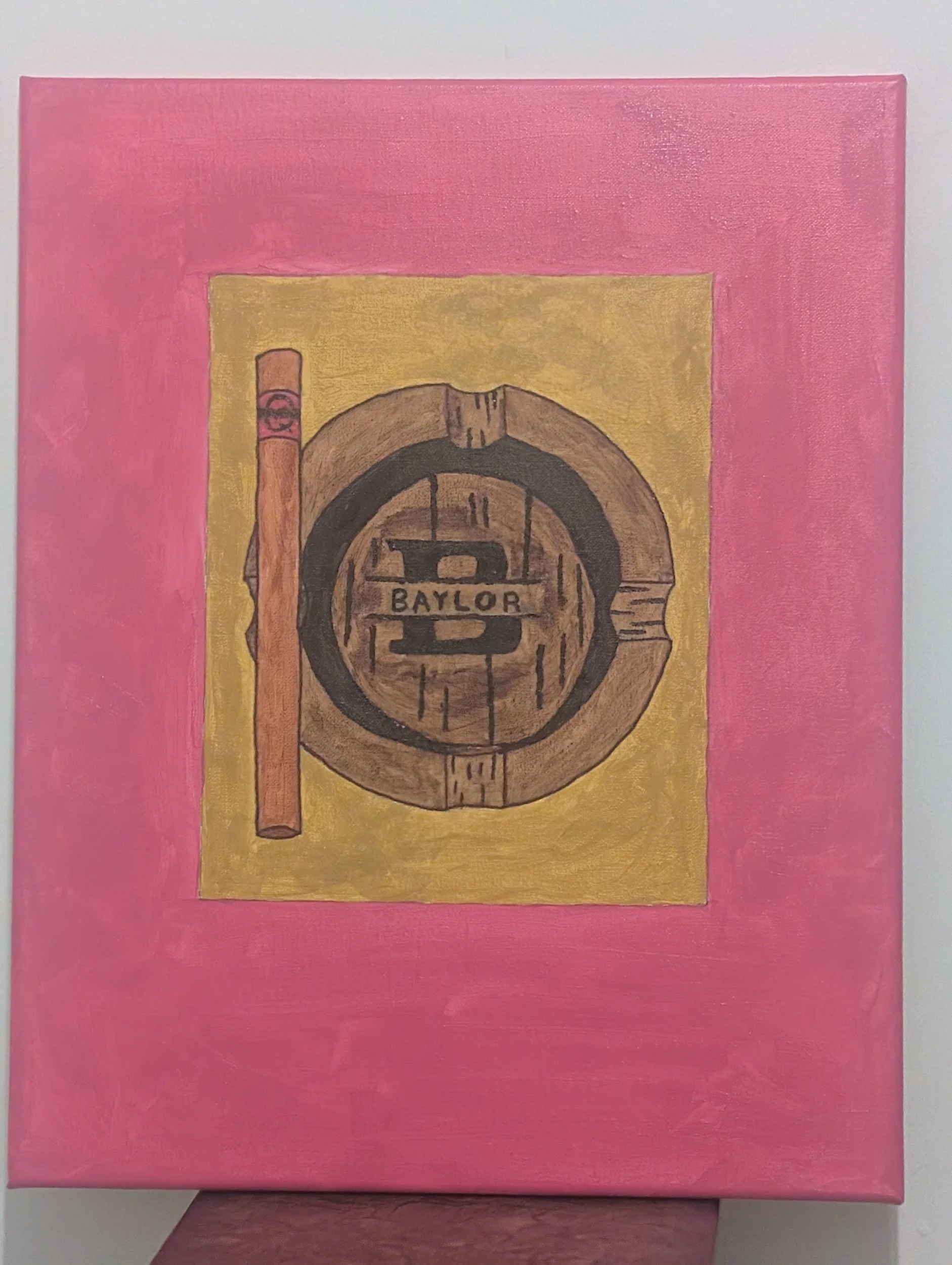 Painting of a wooden Baylor logo with a cigar on a pink background with a yellow center.