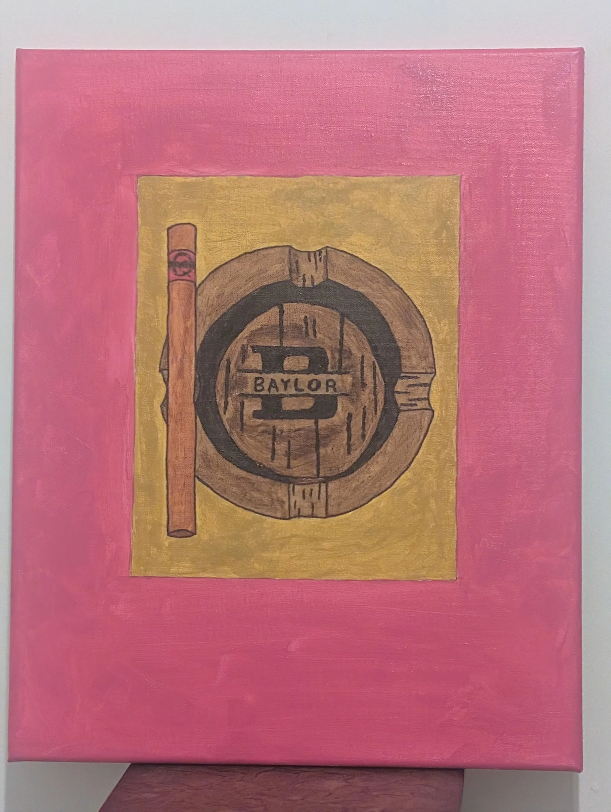 Painting of a wooden Baylor football helmet with stripes on a yellow background, framed by a pink border.