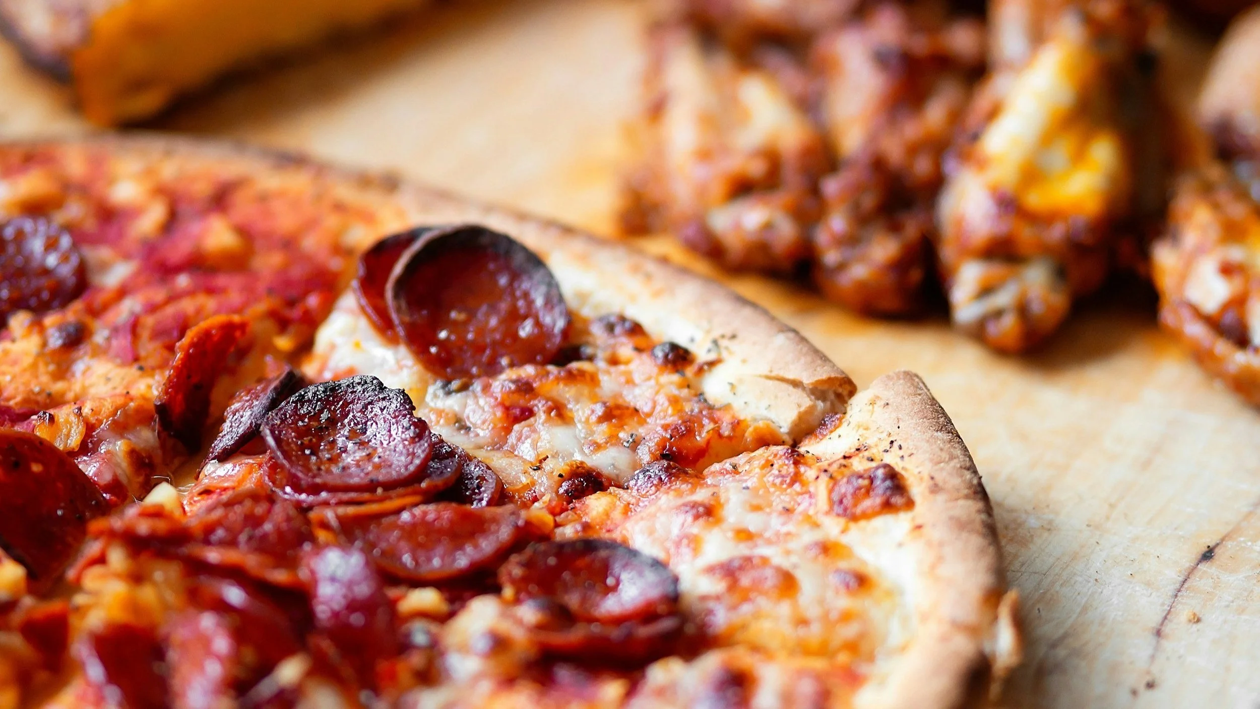 Close-up of a pepperoni and sausage pizza on a wooden surface.