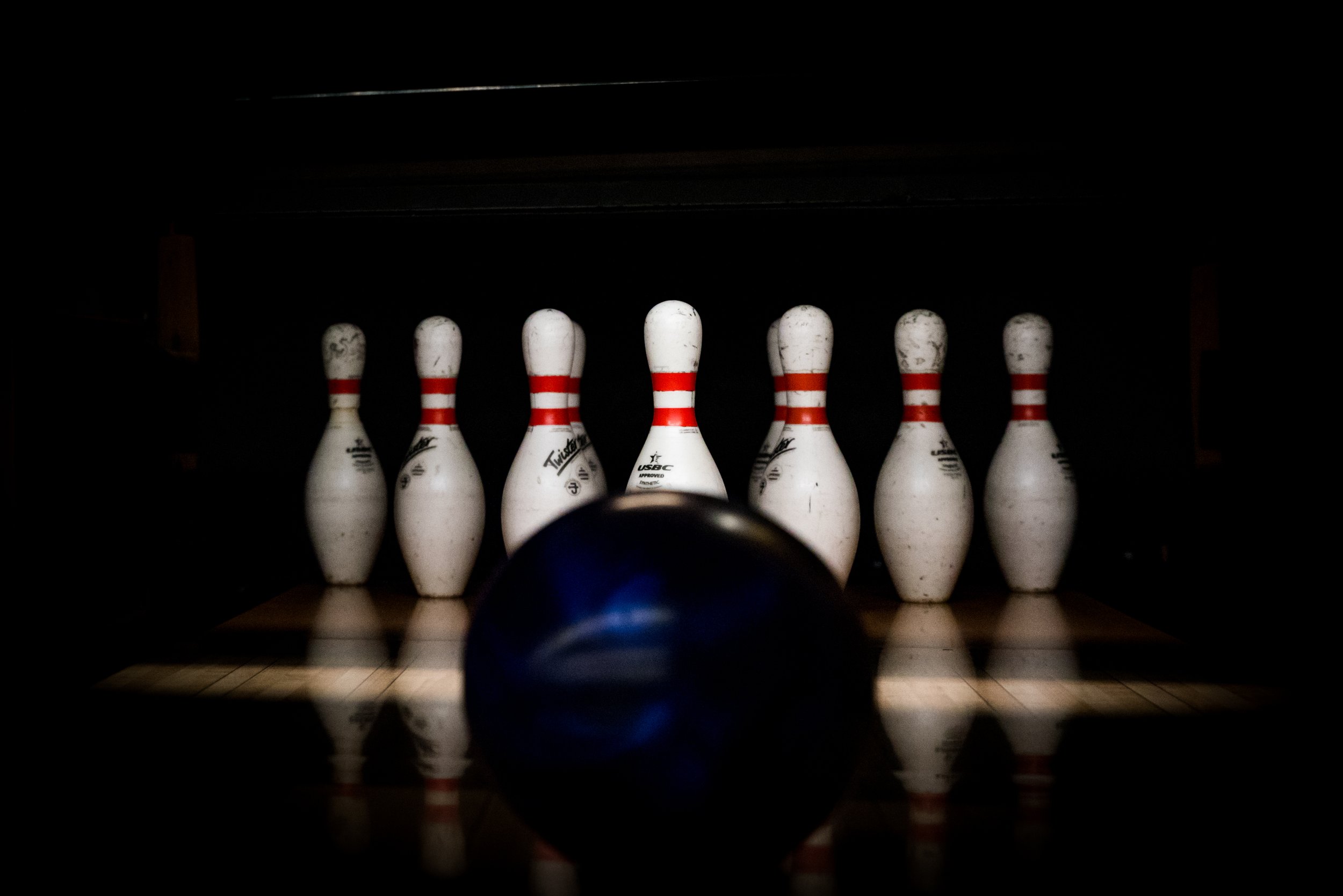 Bowling ball approaching the pins on a bowling alley lane, ready to knock them down.