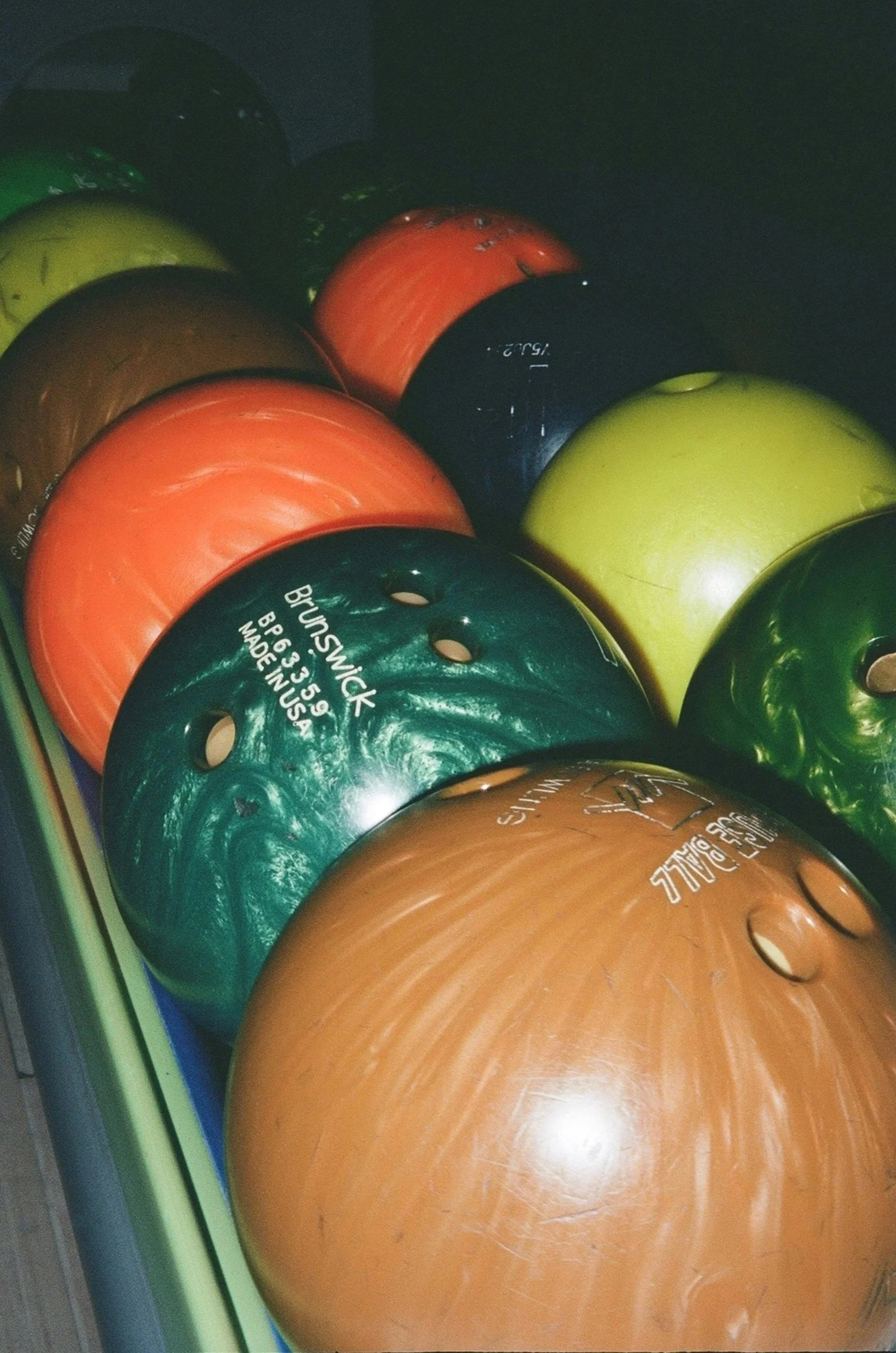 A collection of colorful bowling balls stacked together in a bowling alley.