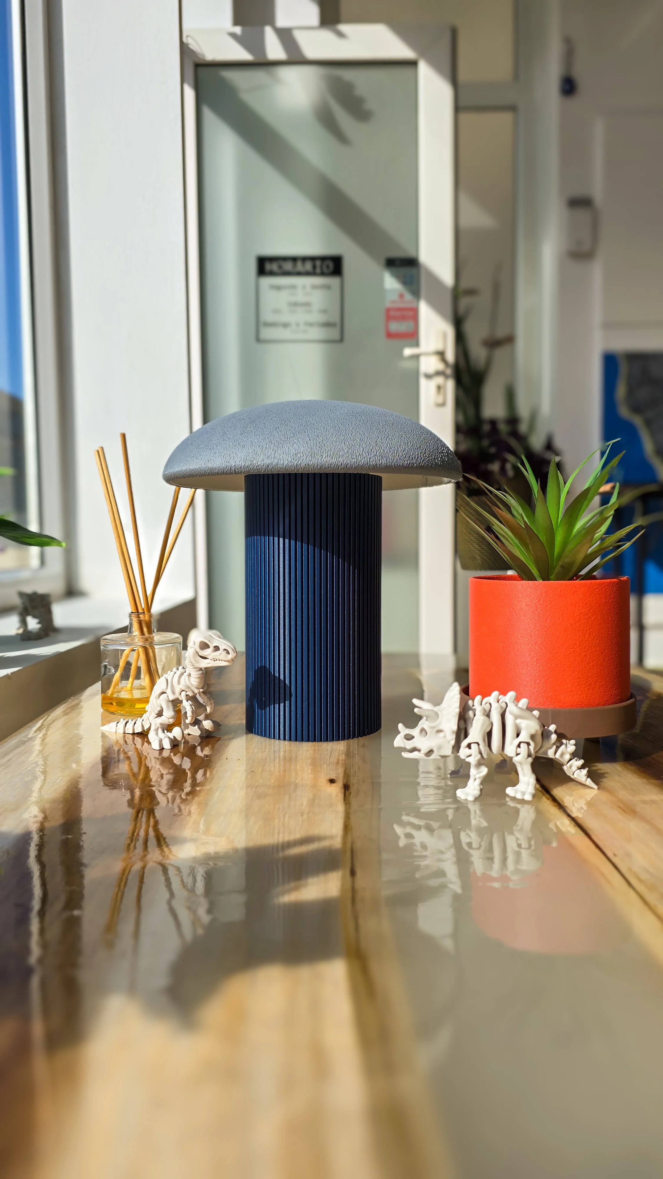 Vasos decorativos com plantas e dinossauros de plástico em uma mesa de madeira, com fundo de uma porta de vidro