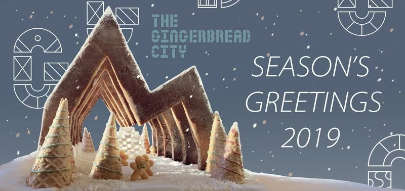 Gingerbread city scene with large gingerbread house and decorated Christmas trees, with text reading "The Gingerbread City, Season's Greetings 2019."