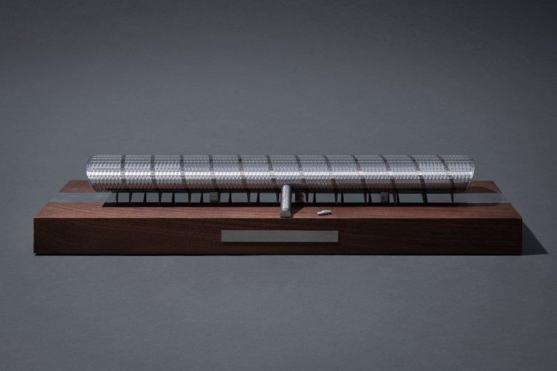 Model of the Foucault pendulum with a long cylindrical arm and a rotating bob, mounted on a wooden base.