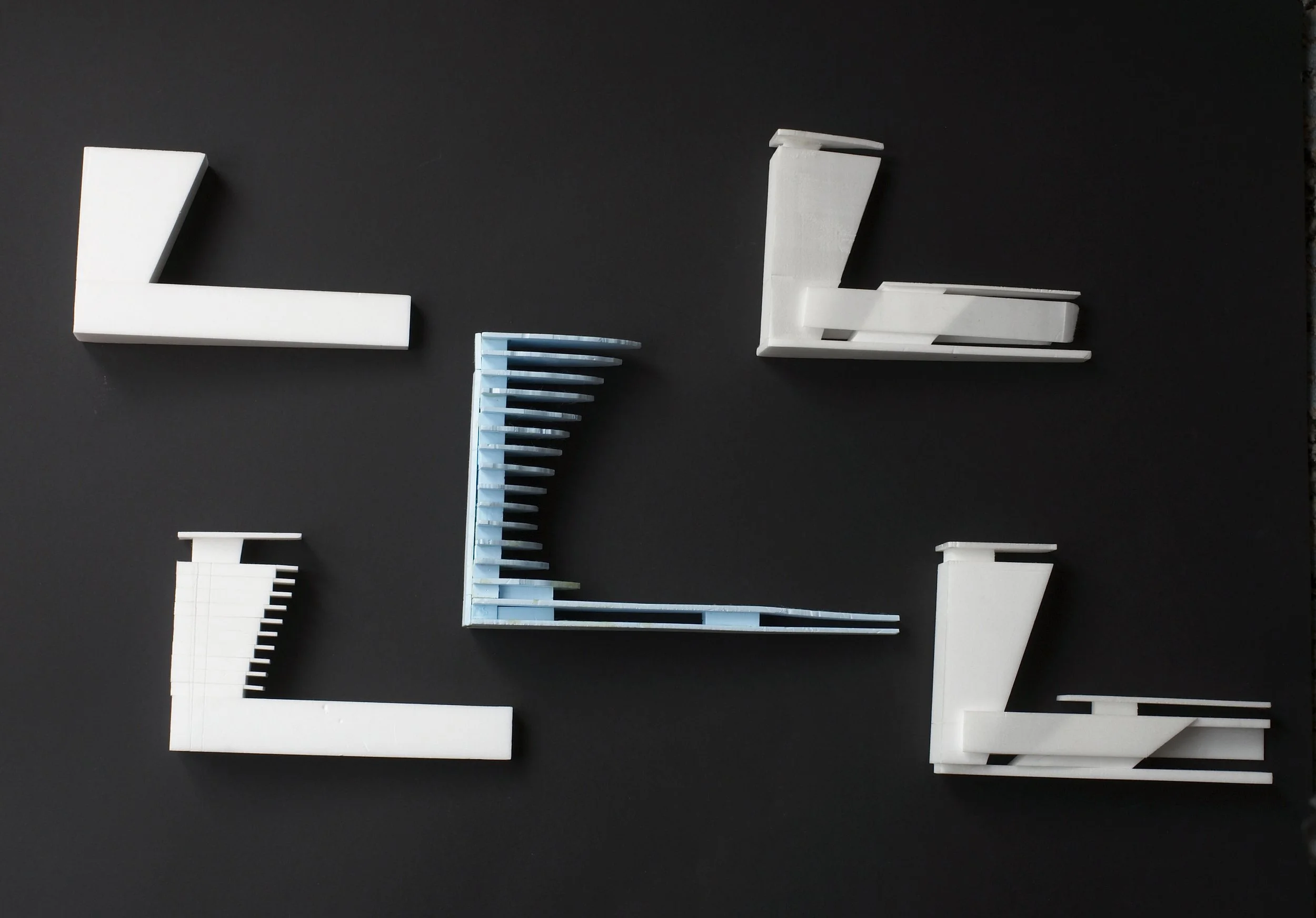 A composition of white, blue, and black building models arranged on a dark flat surface.
