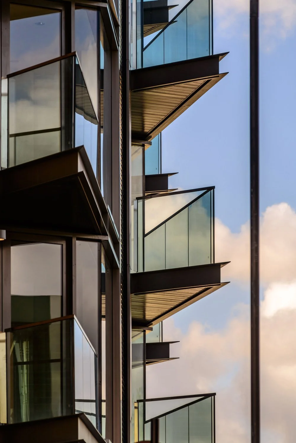 Architectural photograph of the completed Solstice Point facade by NBA, detailing the sharp angles of the cantilevered steel balconies, glass balustrades, and dark metal cladding profiles.