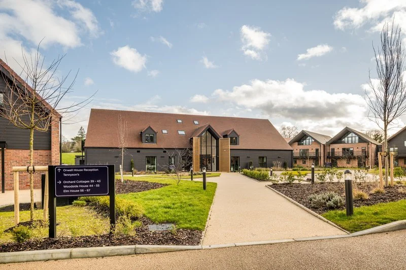 Modern residential building with landscaped pathway and sign with directions.