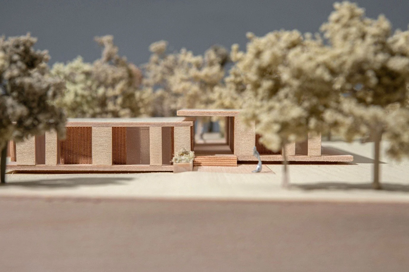 An architectural physical scale model crafted from timber, showcasing a modernist single-story pavilion house design with a central hallway,