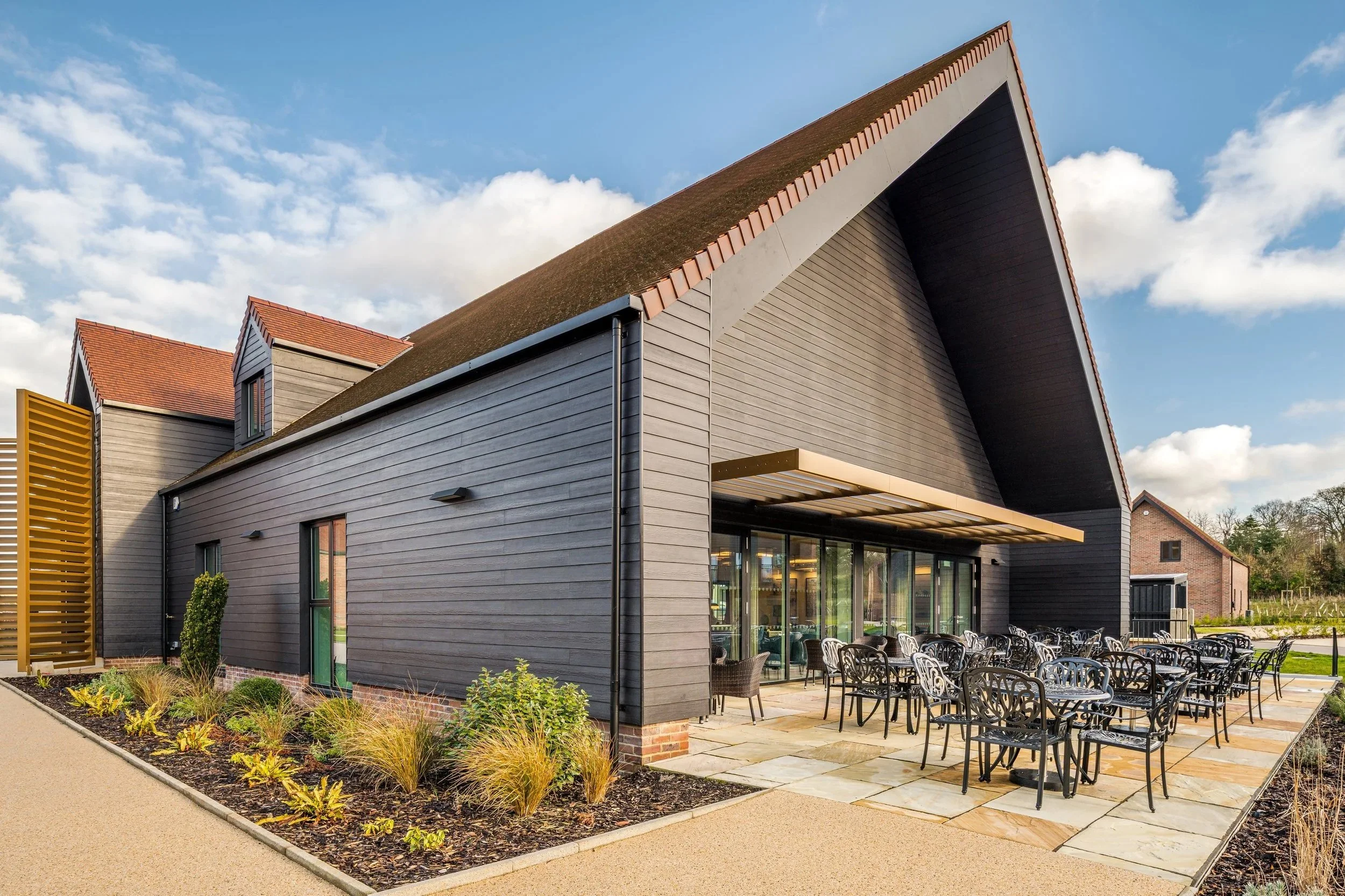 External amenity patio and seating area behind the contemporary gabled clubhouse building at Shiplake Meadows.