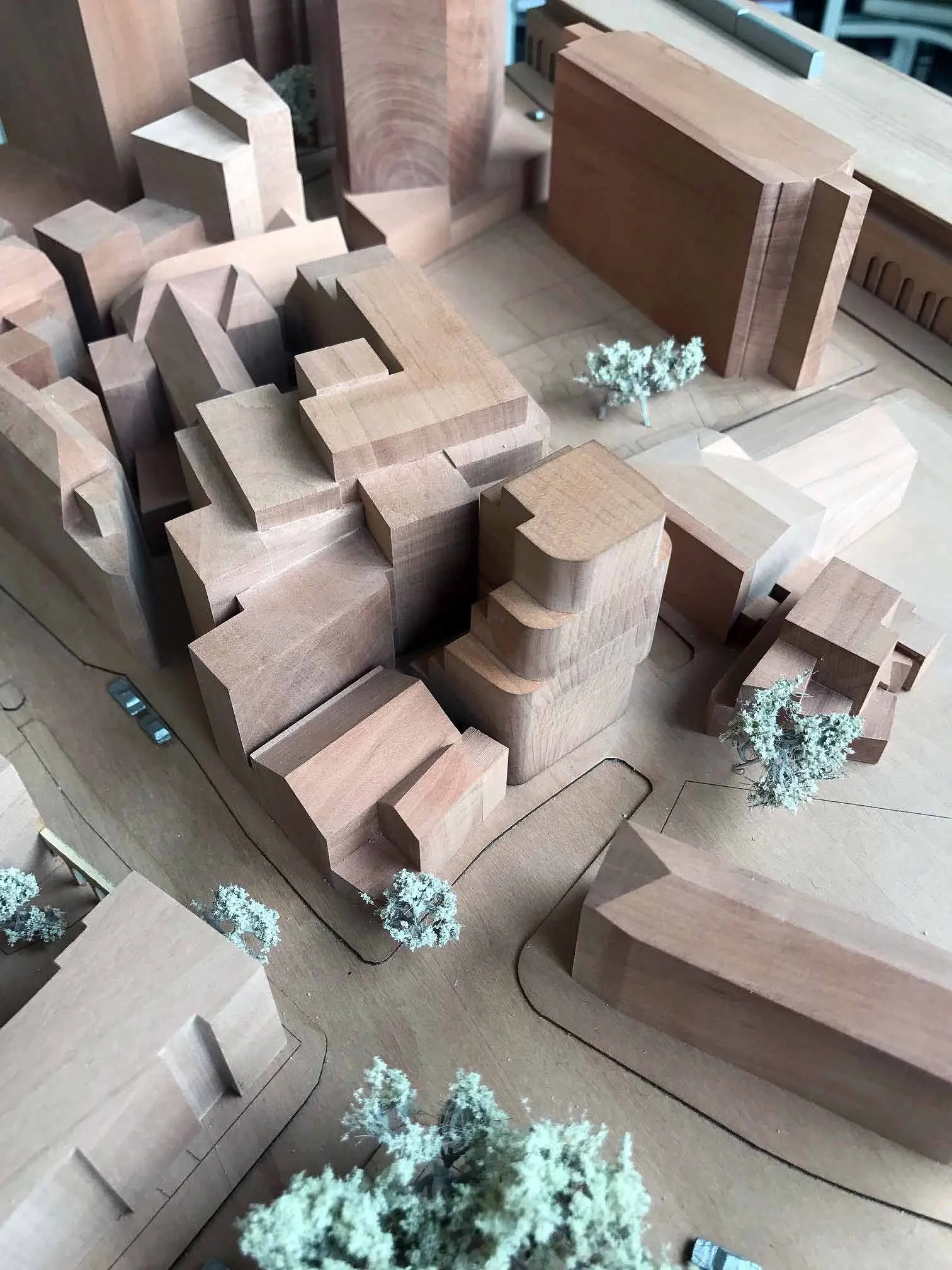 A detailed architectural model of a building complex with multiple wooden structures, including trees and pathways.