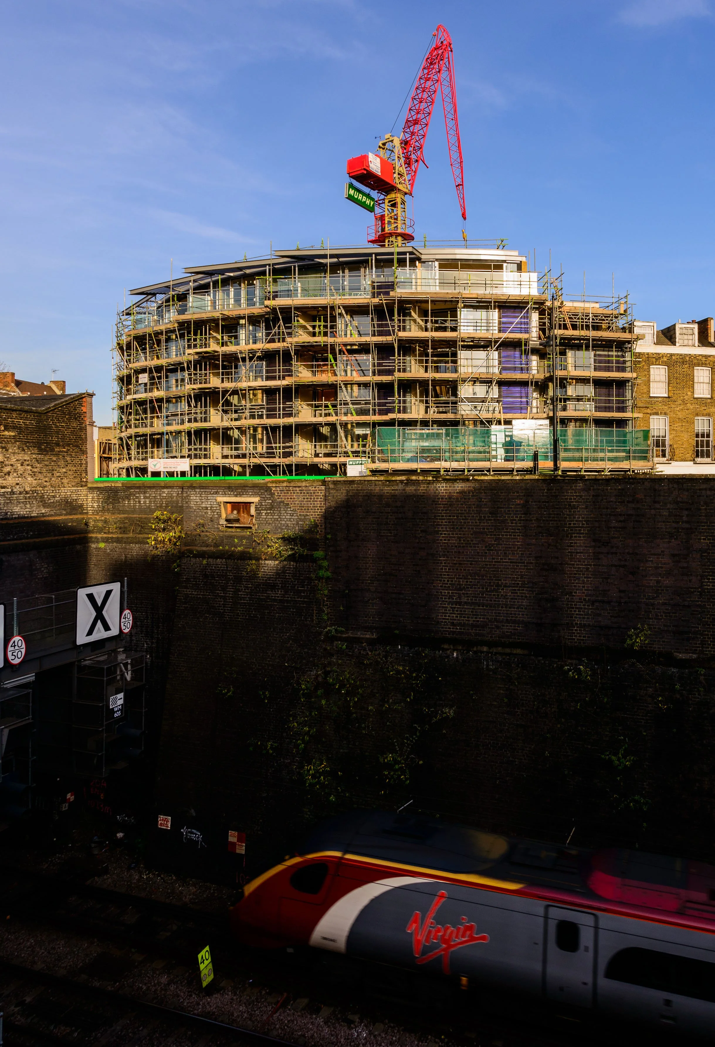 Construction site progress at Solstice Point by NBA, showcasing structural glazing panel installation on a modern 5-storey building facade.