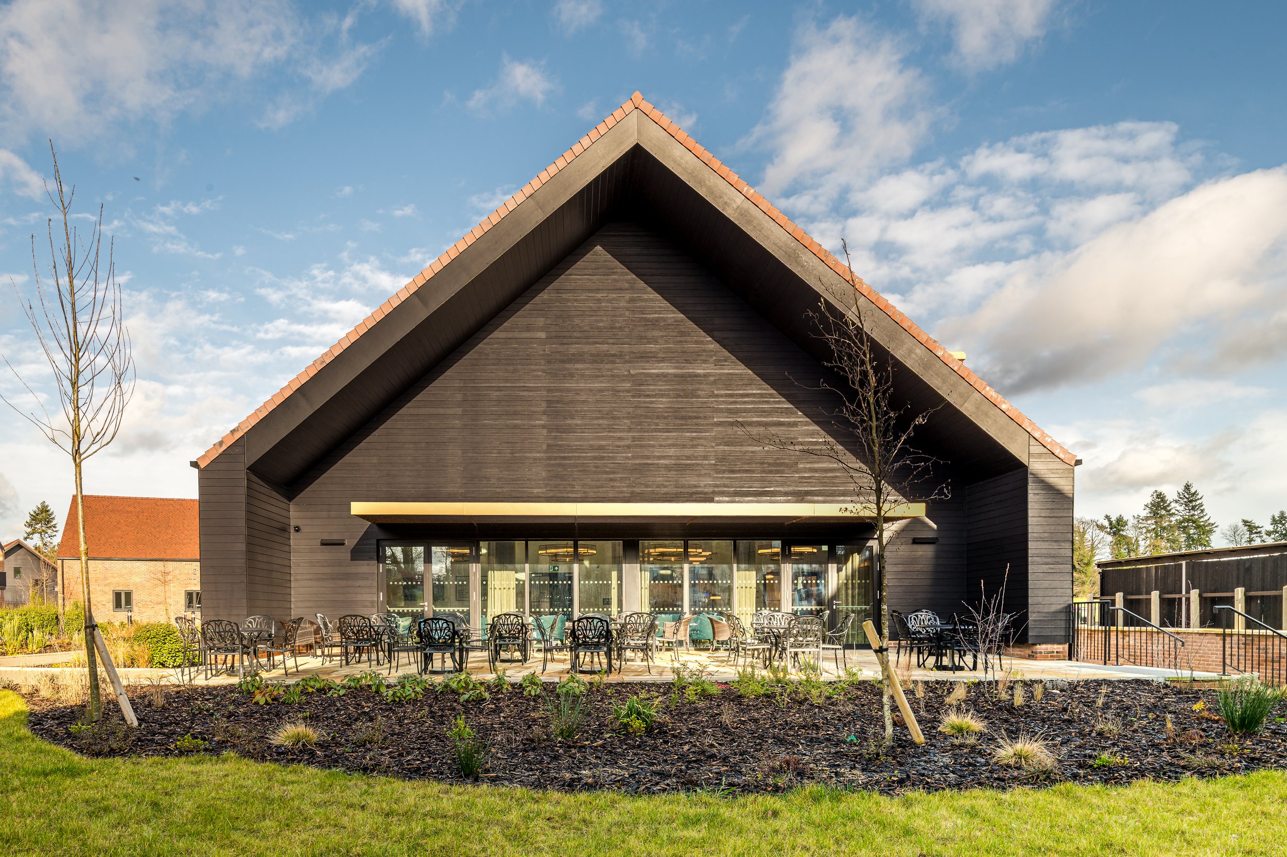 External amenity patio and seating area behind the contemporary gabled clubhouse building at Shiplake Meadows.