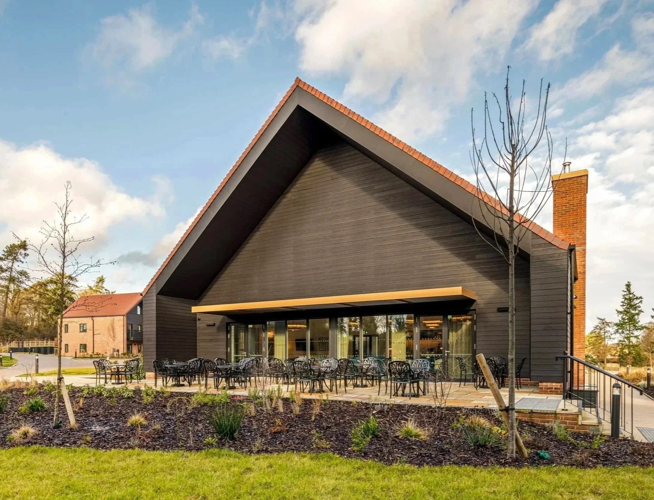 External amenity patio and seating area behind the contemporary gabled clubhouse building at Shiplake Meadows.