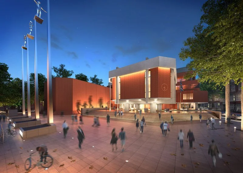 Night view of a modern theater or cultural center with a large illuminated digital clock on the front facade, surrounded by trees and people walking on a plaza with stairs.