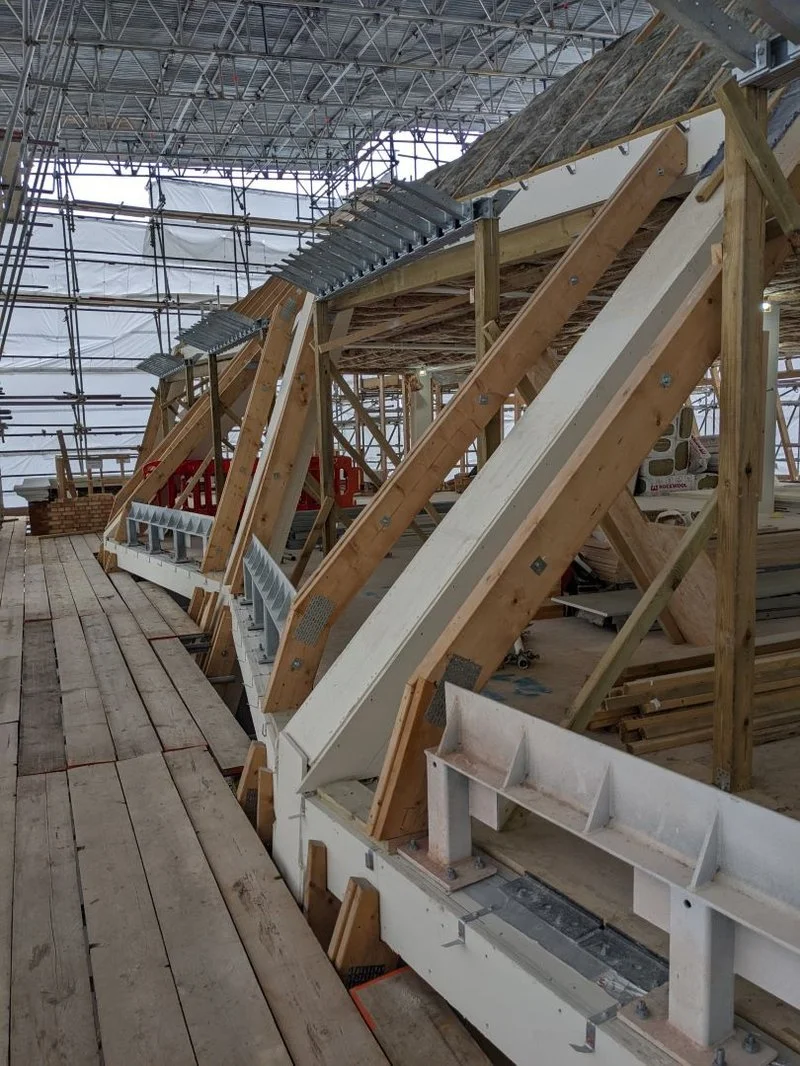 Construction site with wooden framework and scaffolding, possibly for building a roof or a new structure.